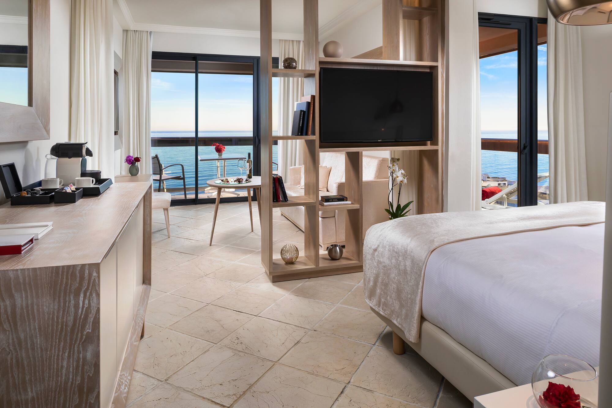 Luxury hotel suite with sea view balcony, modern decor, and living space.