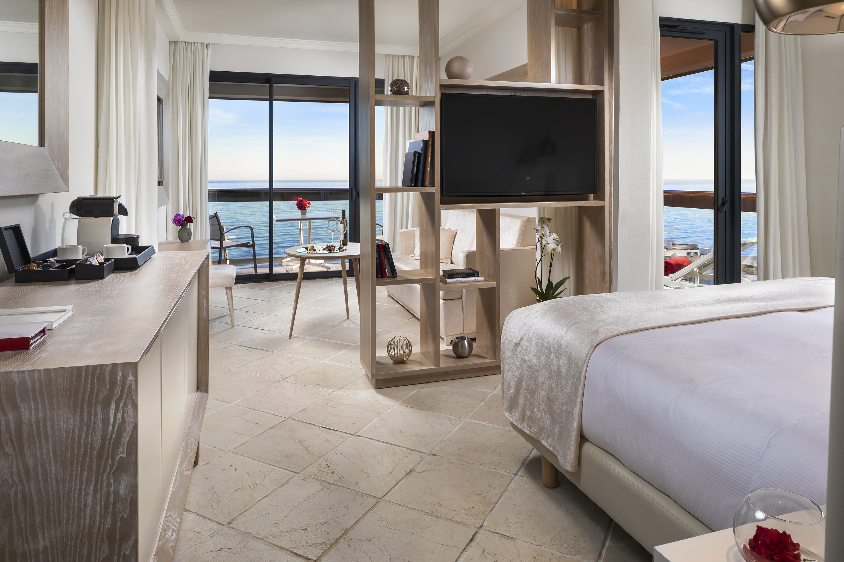 Luxury hotel suite with sea view balcony, modern decor, and living space.
