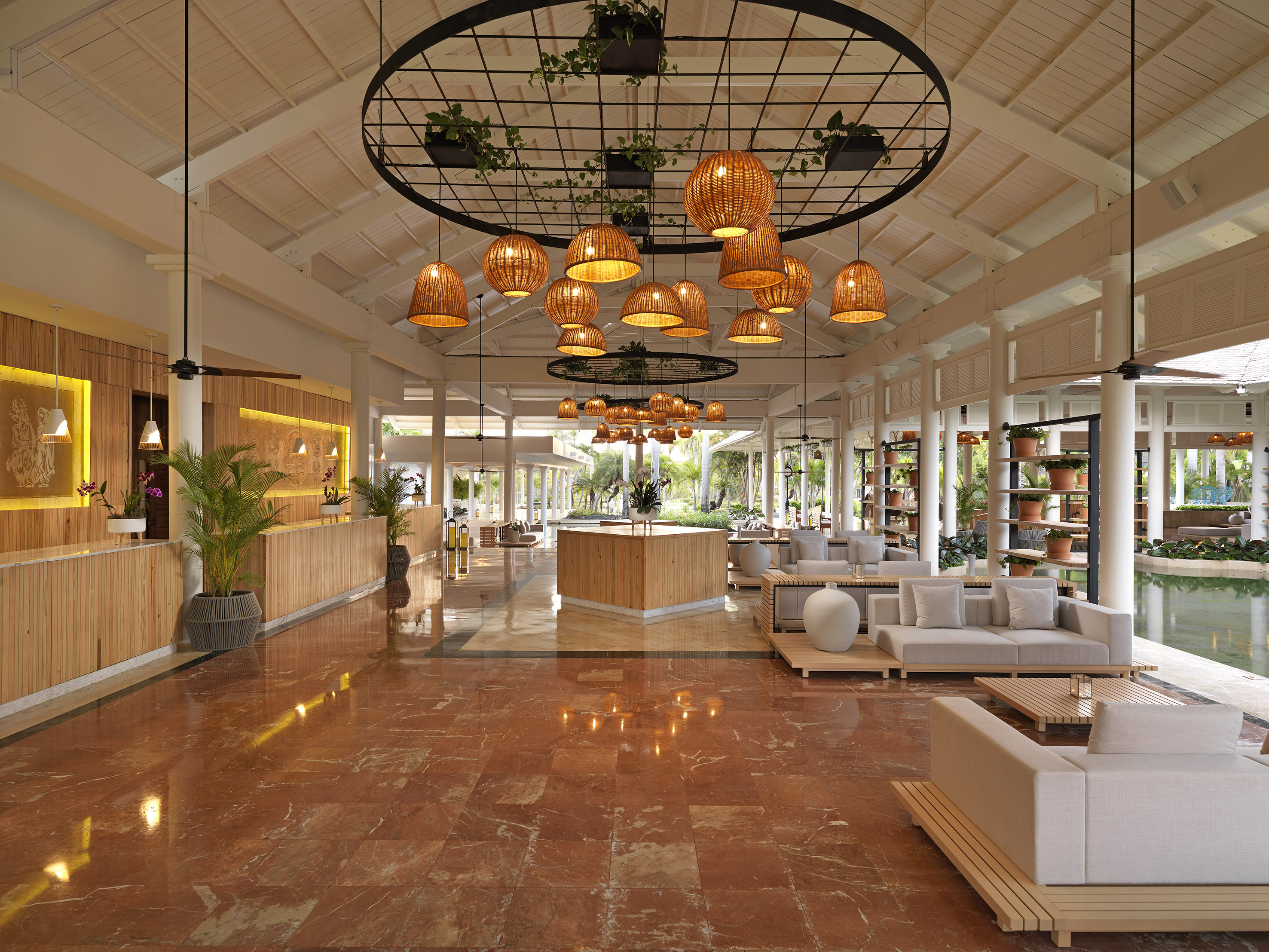 Luxury hotel lobby with red marble floor, modern seating, and rattan lights.