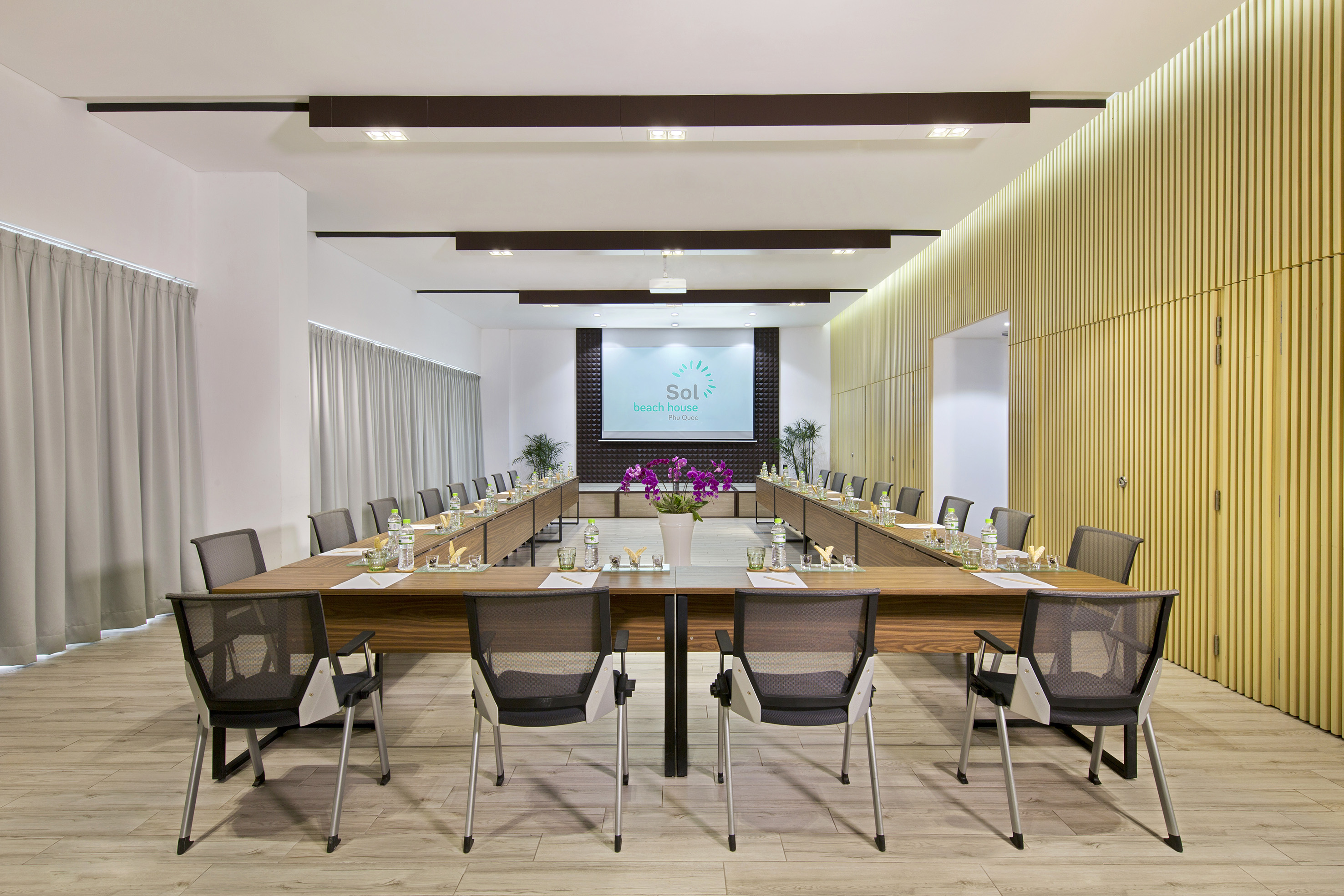 Sol Beach House conference room with U-shaped table and projector screen.