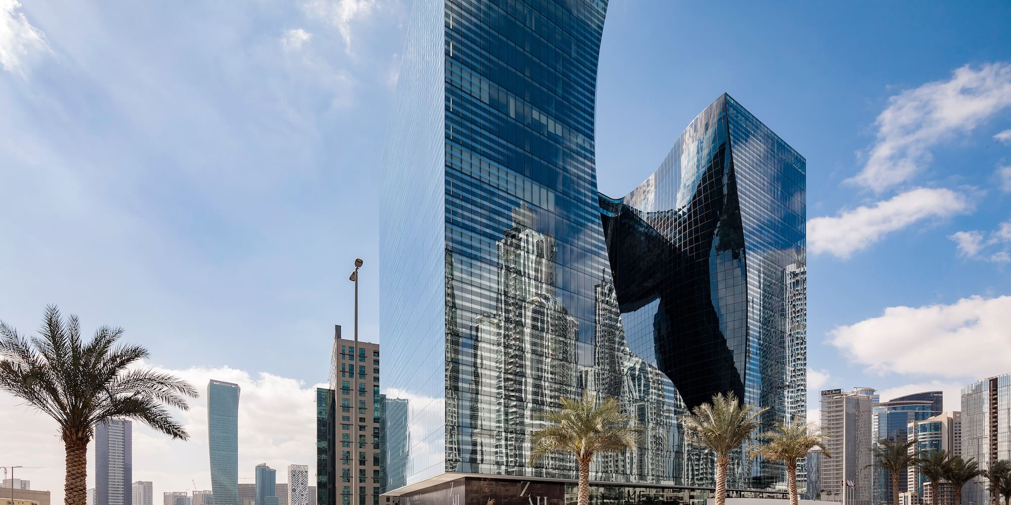 a tall glass buildings with palm trees