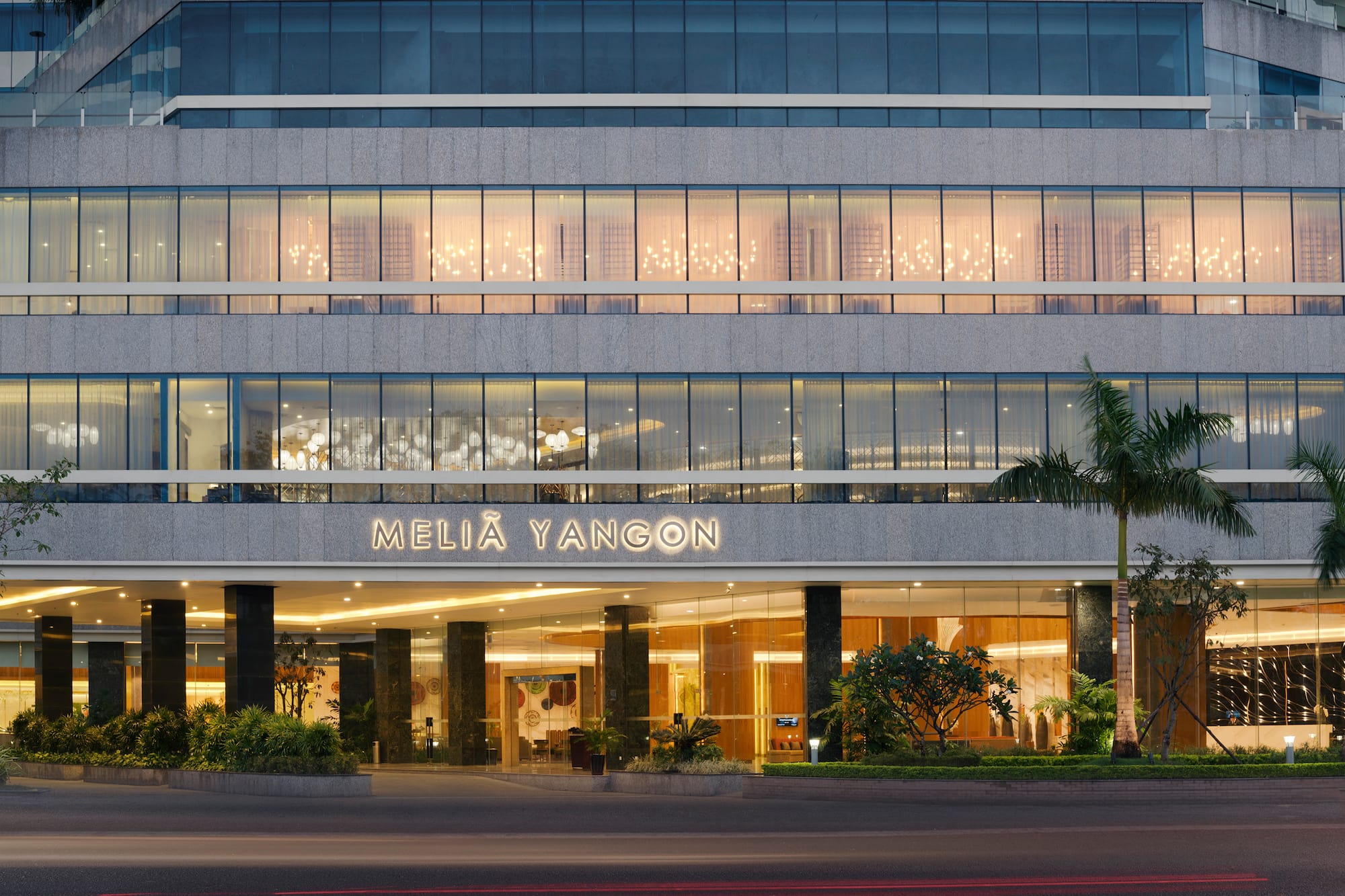 Melia Yangon hotel exterior, modern glass facade with illuminated entrance.
