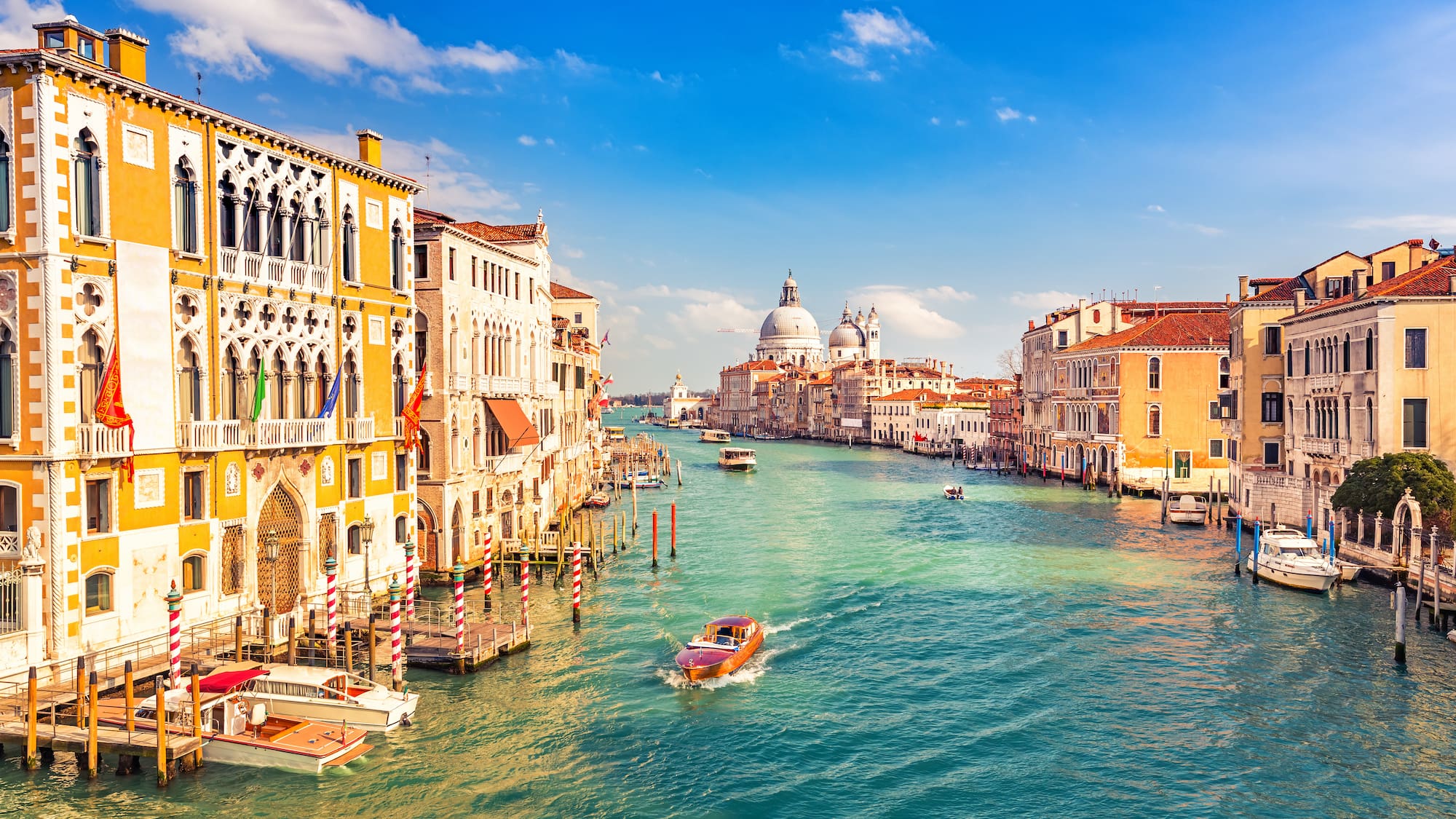 a water way with boats and buildings in the background with Grand Canal in the background