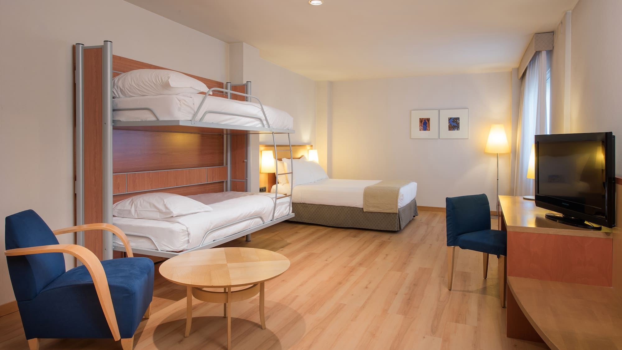 Hotel family room with bunk beds, double bed, and desk.