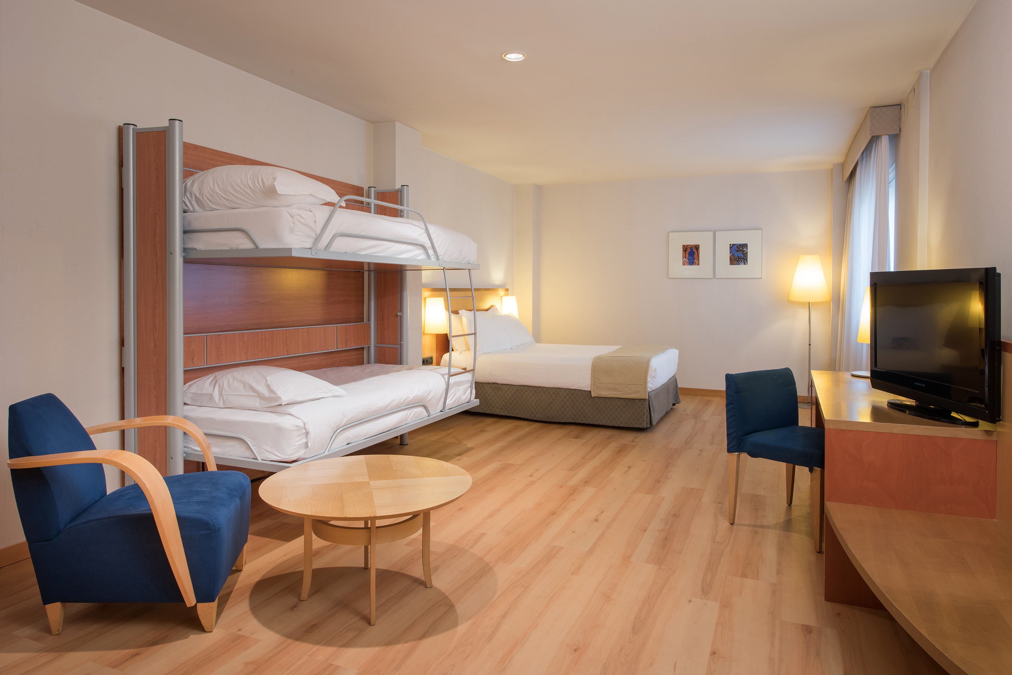 Hotel family room with bunk beds, double bed, and desk.