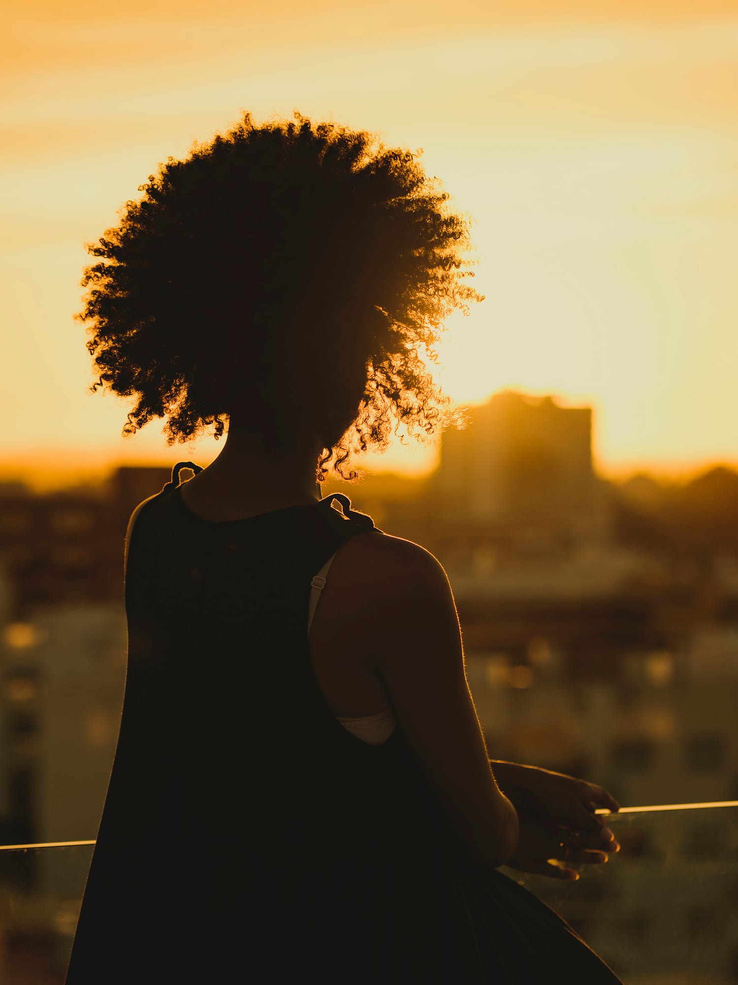 a silhouette of a woman with a sunset behind her