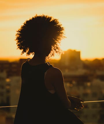 a silhouette of a woman with a sunset behind her