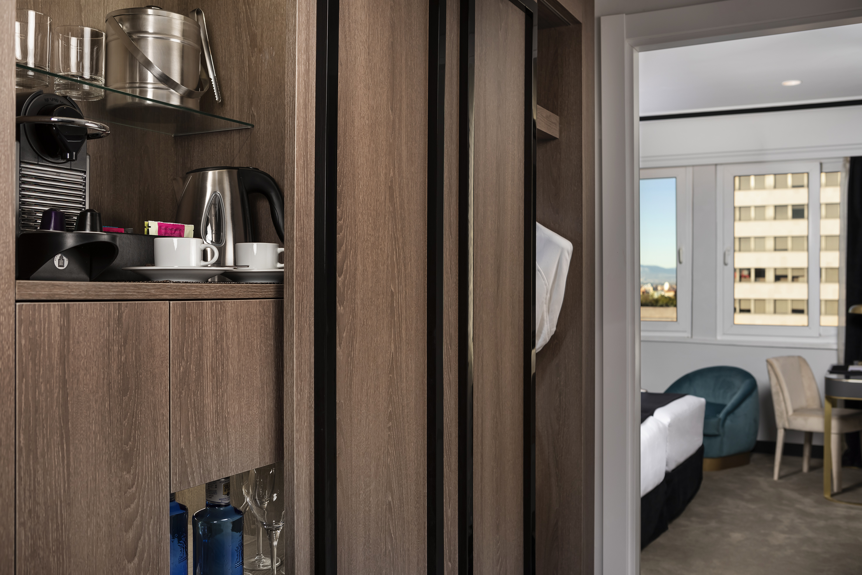 Hotel room minibar, coffee machine, kettle, ice, wardrobe, and city view.