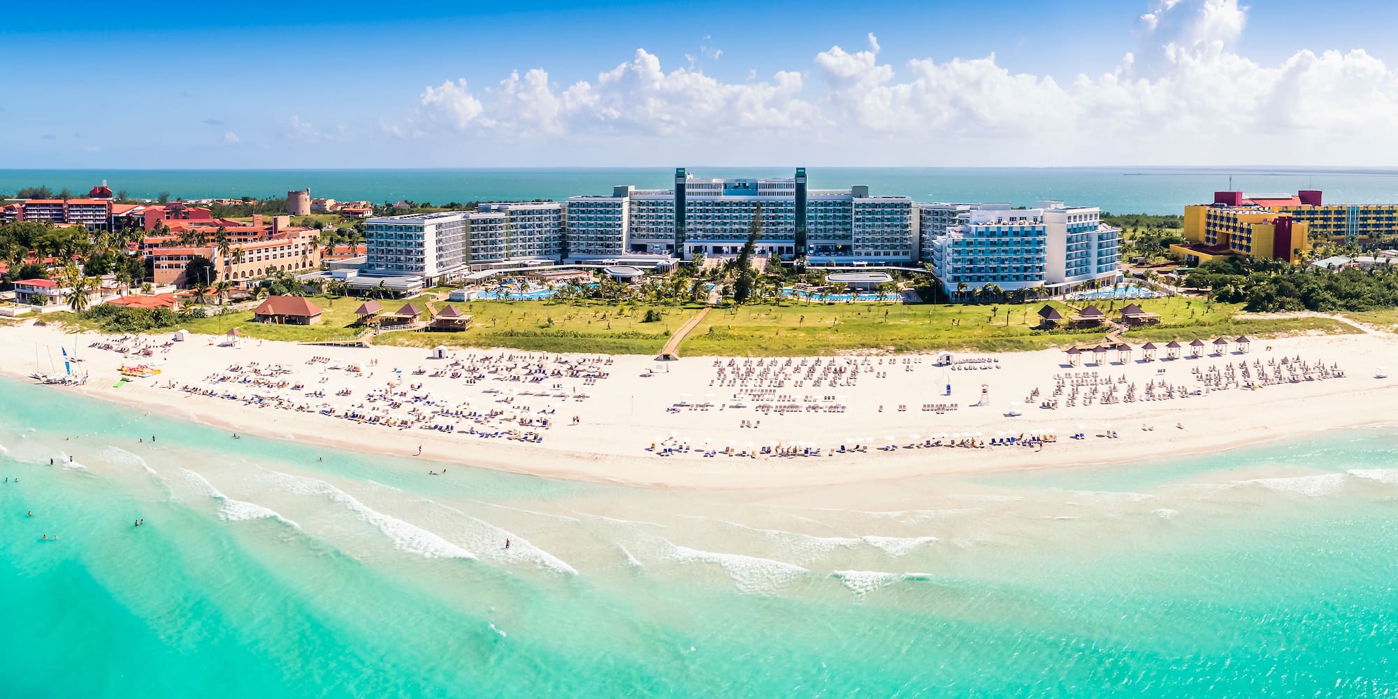 a beach with many people and buildings