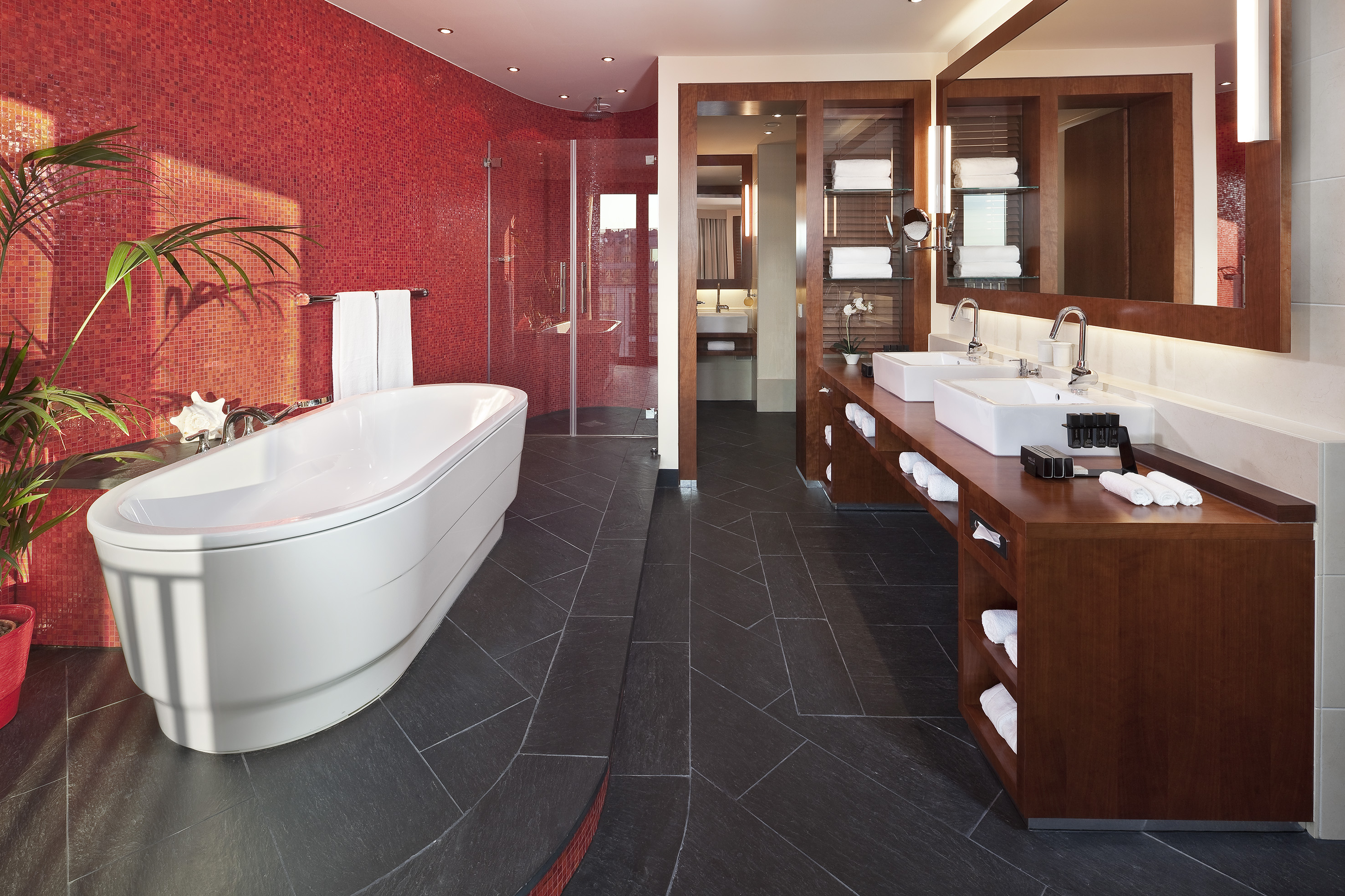 Modern bathroom: red mosaic wall, freestanding tub, and double vanity.