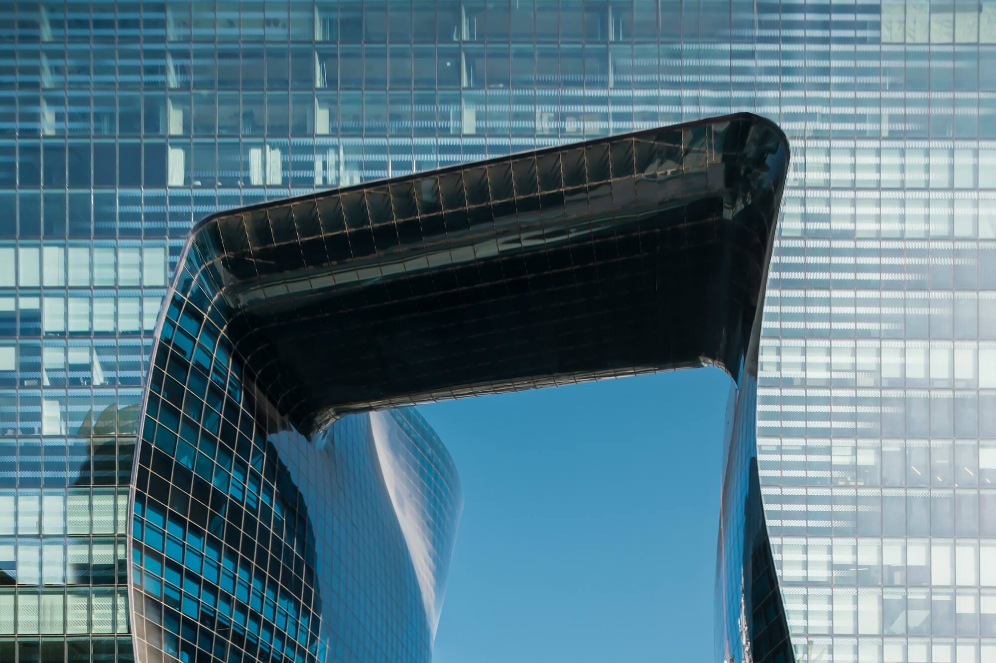Modern glass building with sculptural, reflective opening.