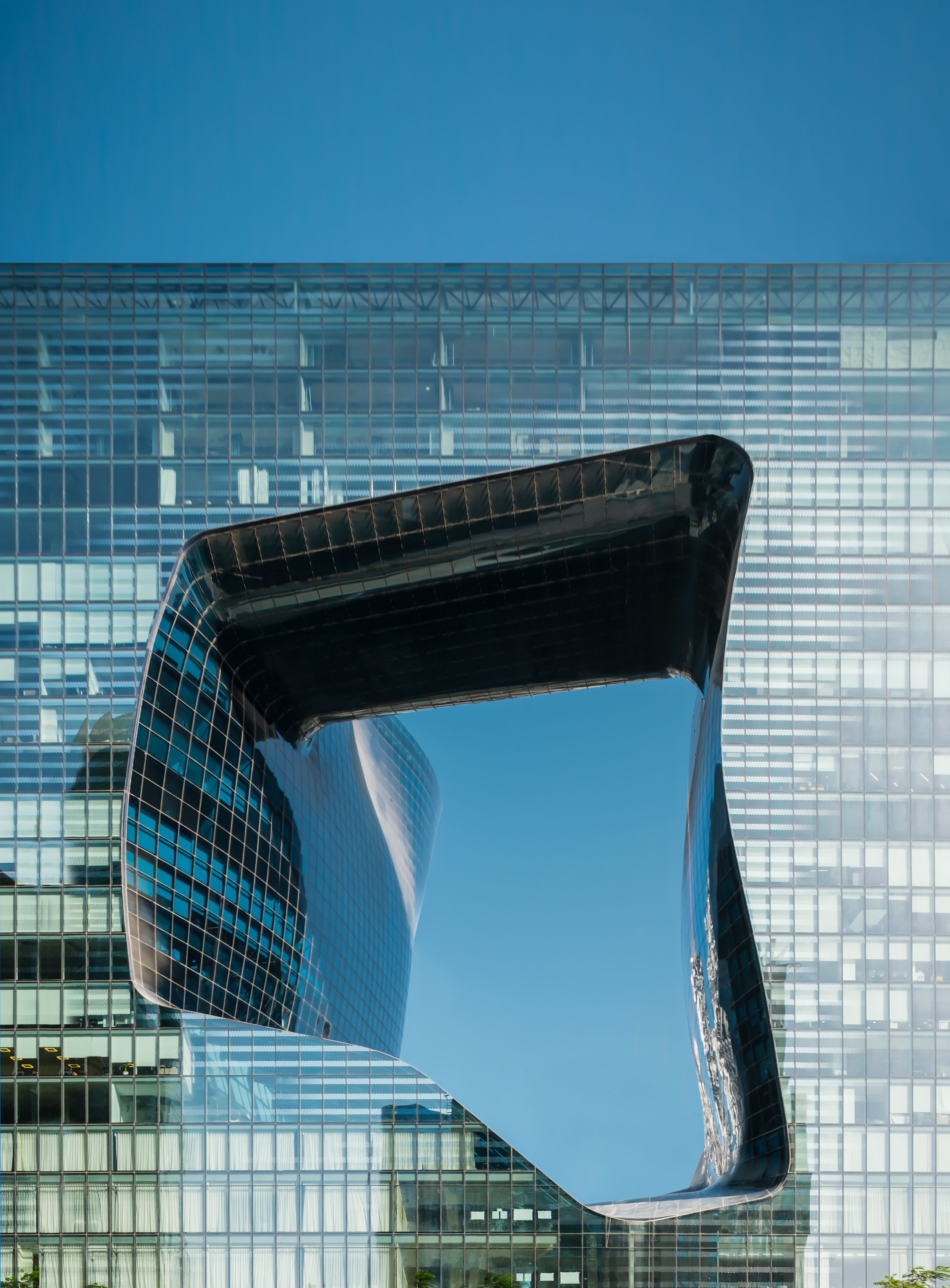 Modern glass building with sculptural, reflective opening.