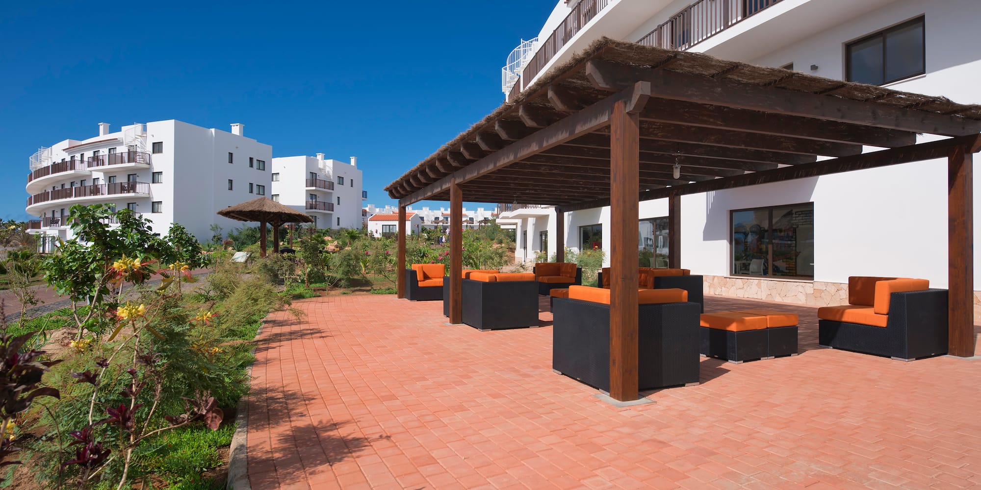 a patio with a covered area and a building with white buildings