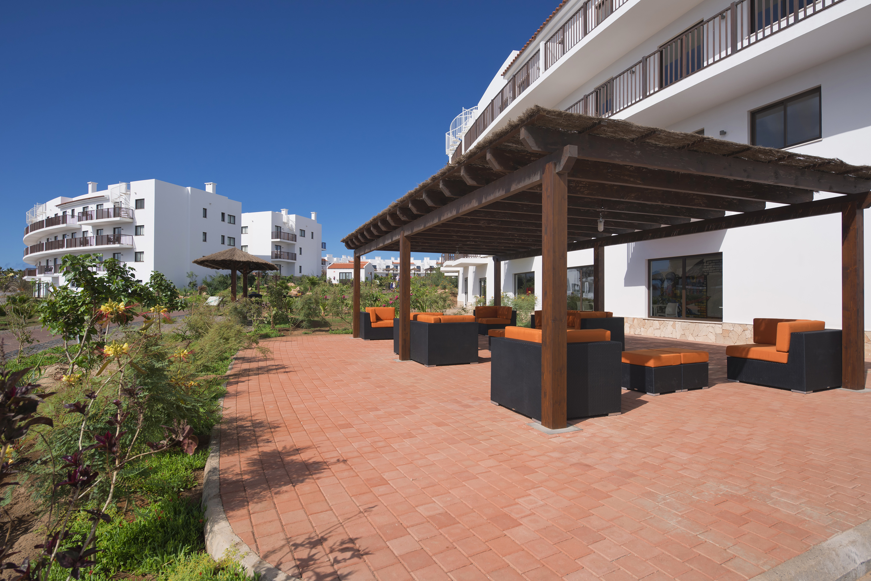 a patio with a covered area and a building with white buildings
