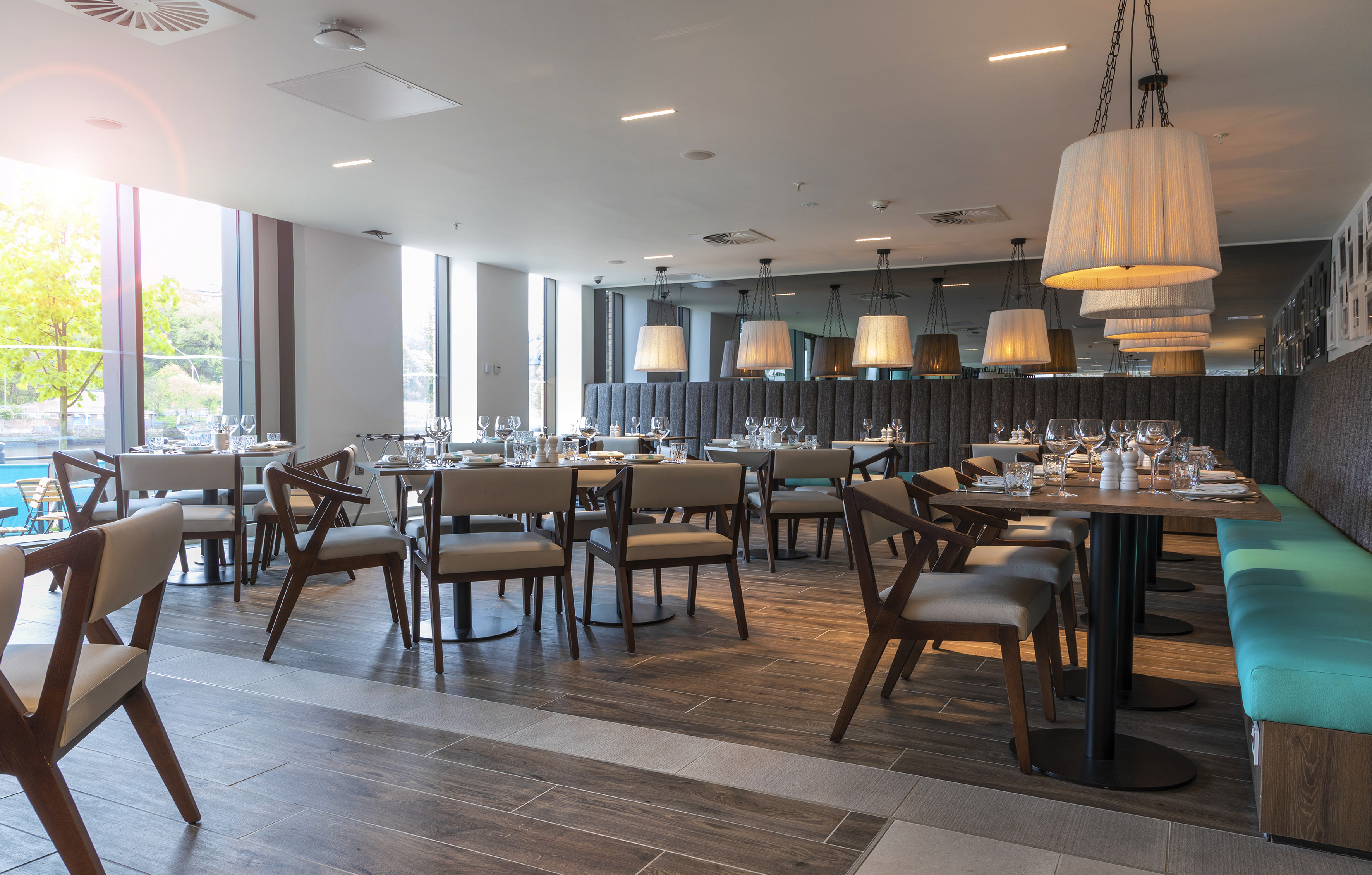 Modern restaurant dining area with large windows, tables, and pendant lights.