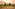 a rice field with buildings and a cloudy sky