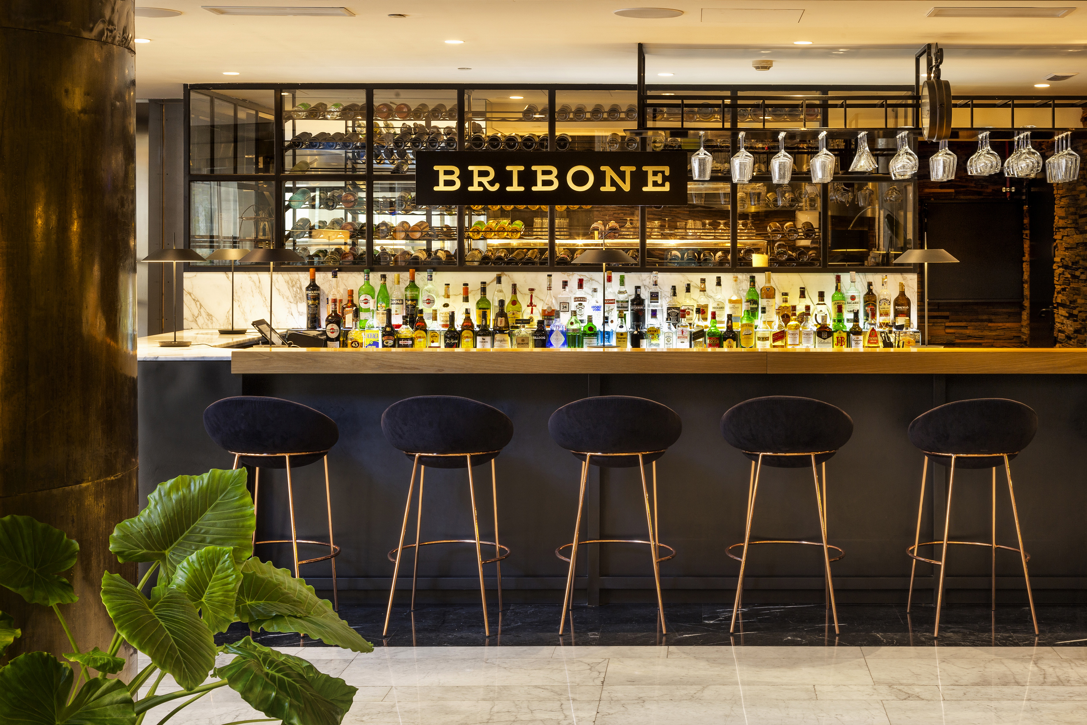 a bar with black chairs and bottles