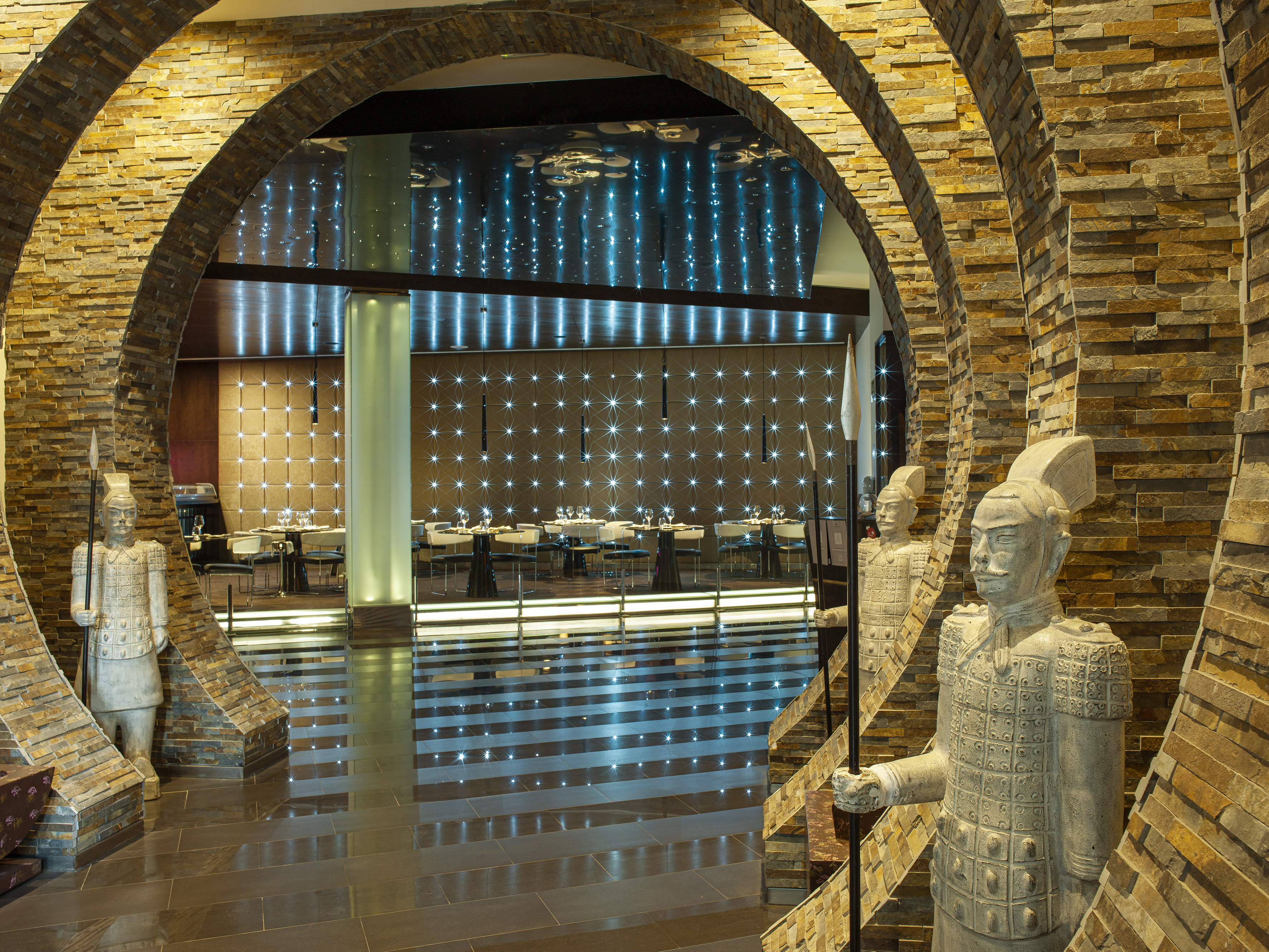 Stone archway to modern Asian restaurant with terracotta warrior statues.