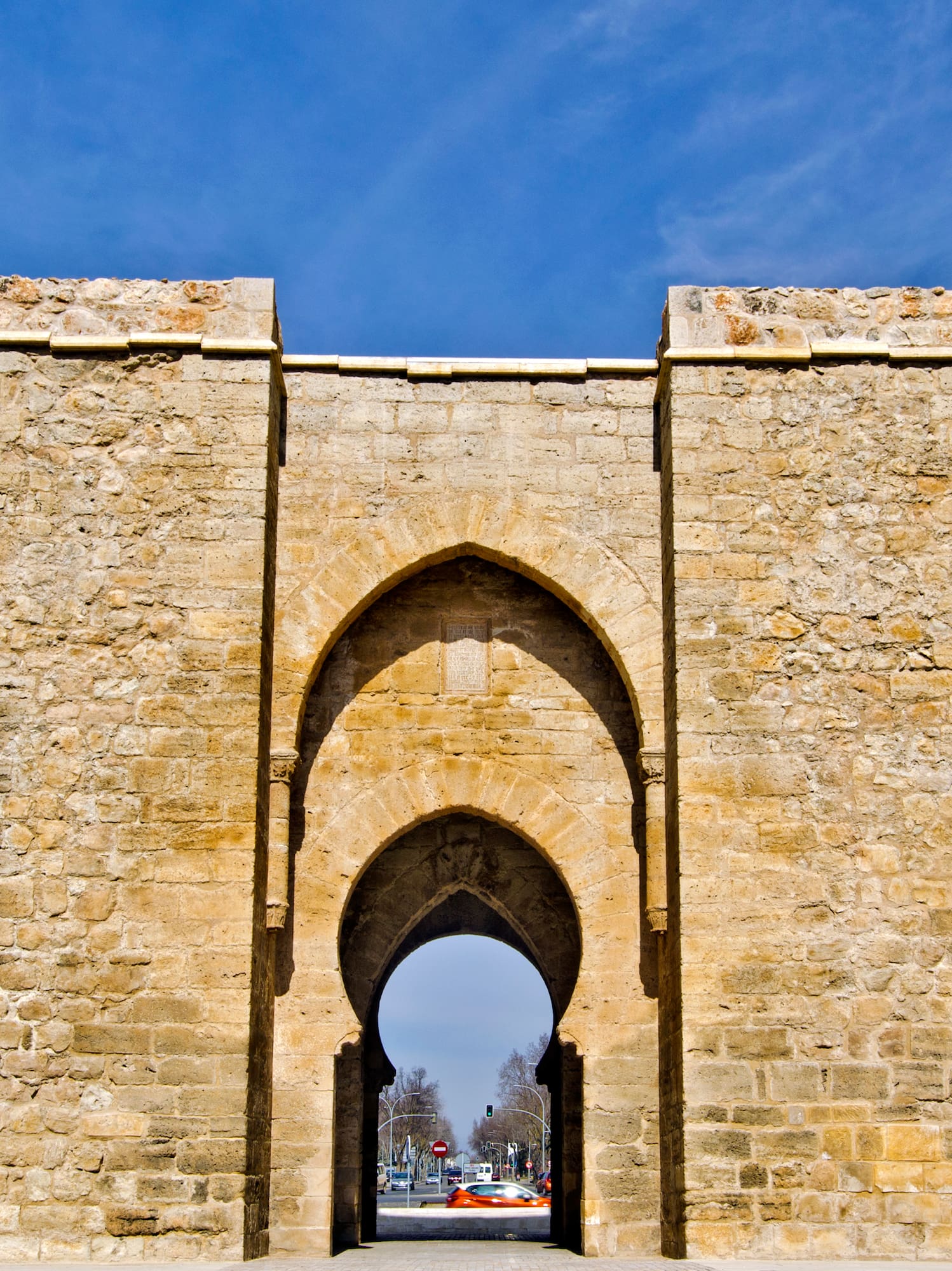 a stone archway with a blue sky with Torre de la Malmuerta in the background