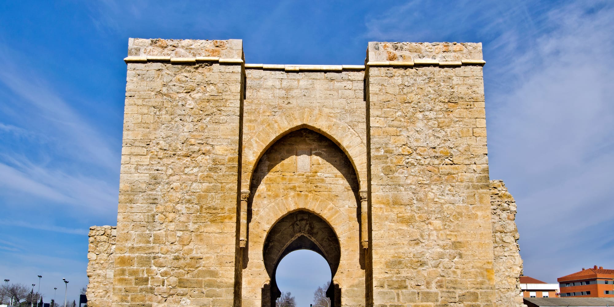 a stone archway with a blue sky with Torre de la Malmuerta in the background