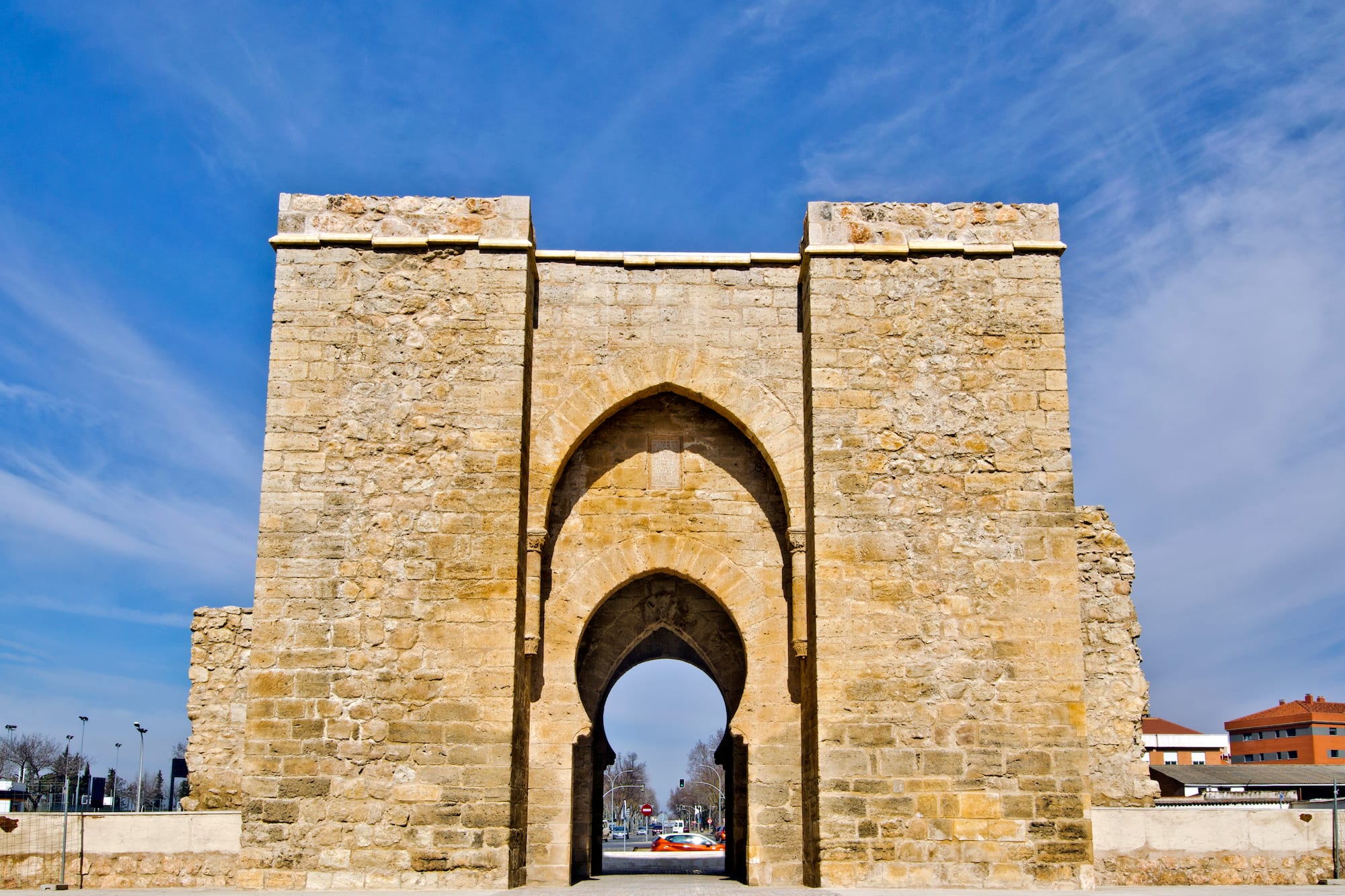 a stone archway with a blue sky with Torre de la Malmuerta in the background