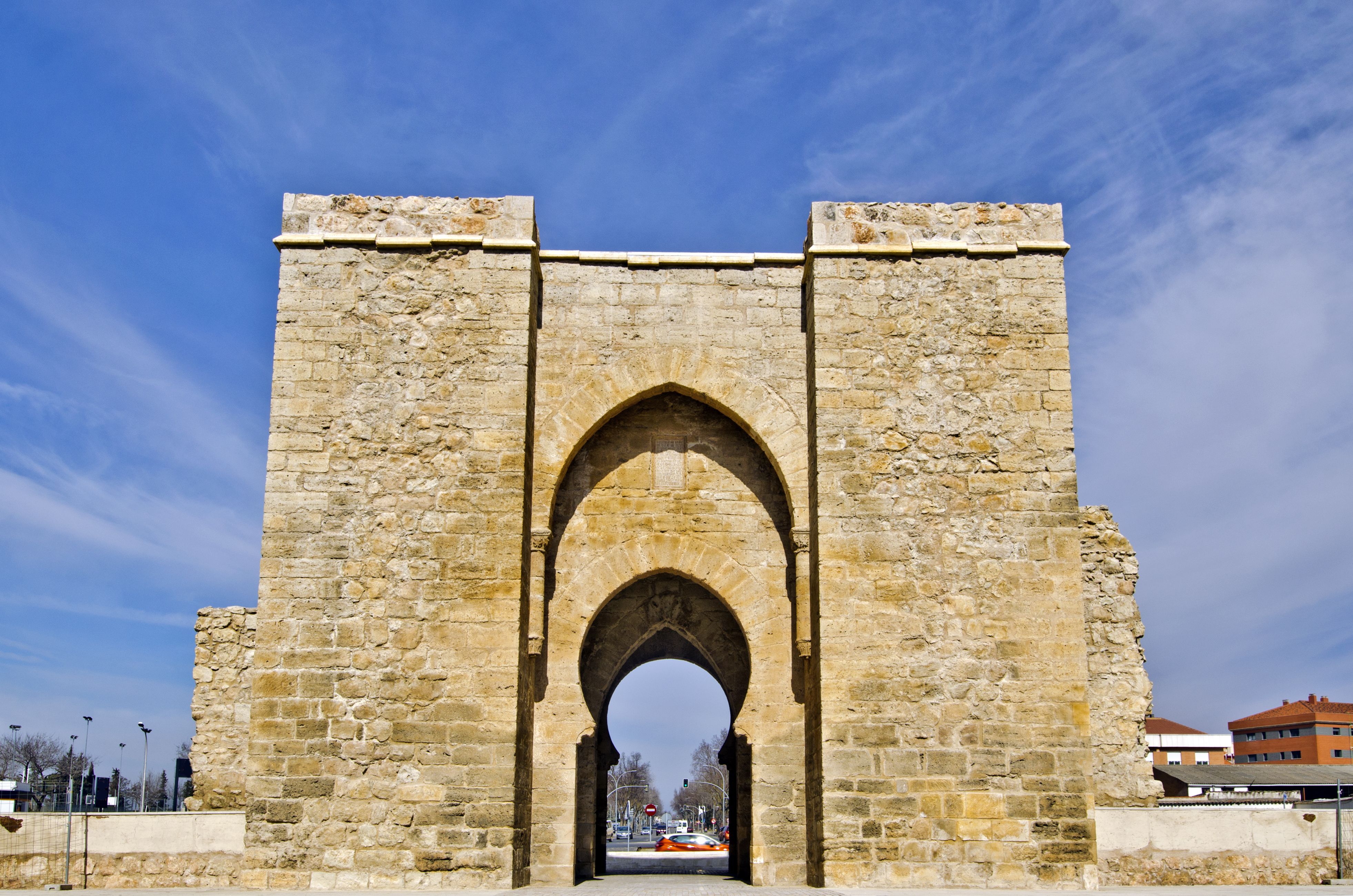 a stone archway with a blue sky with Torre de la Malmuerta in the background