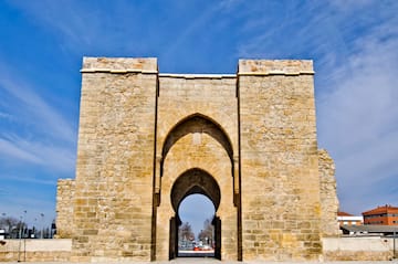a stone archway with a blue sky with Torre de la Malmuerta in the background