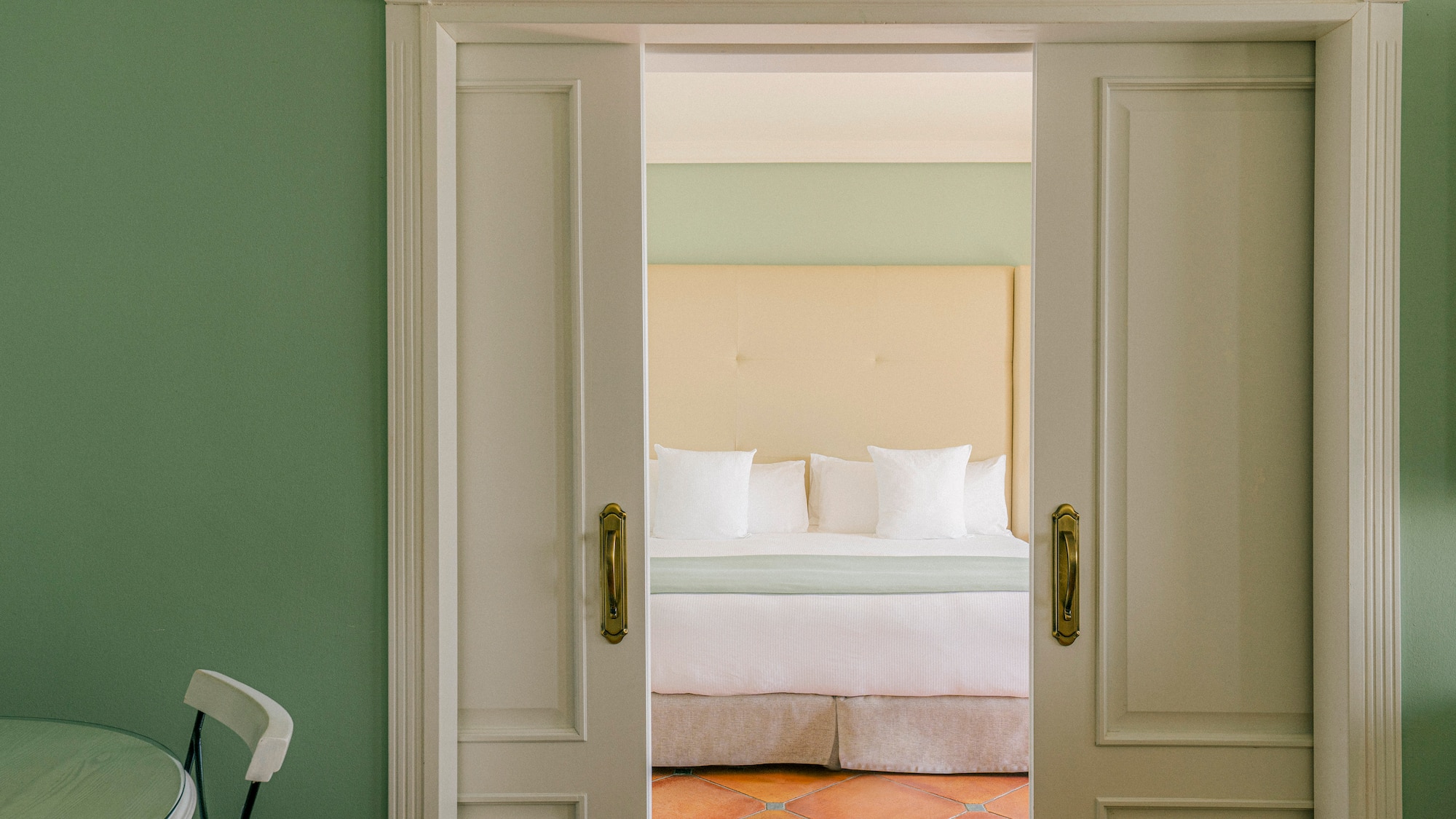 a door with a bed and a chair in the background