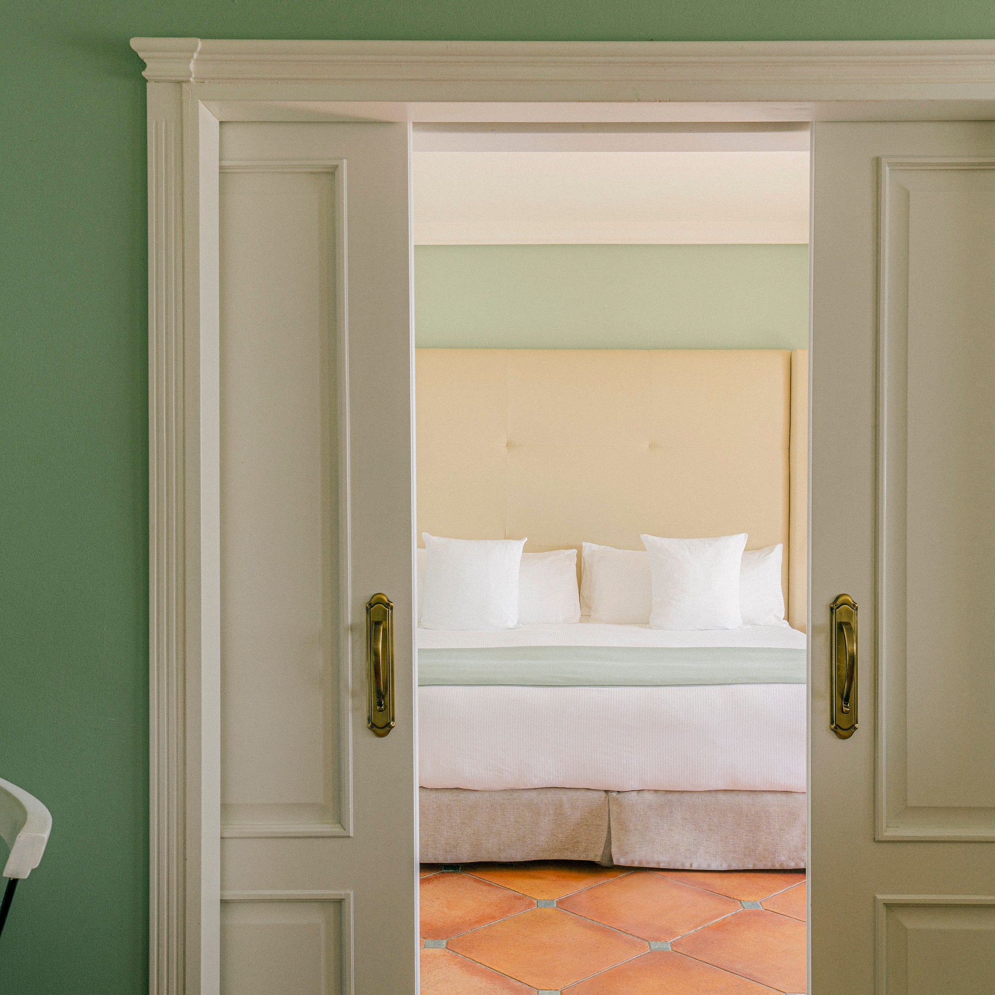 a door with a bed and a chair in the background