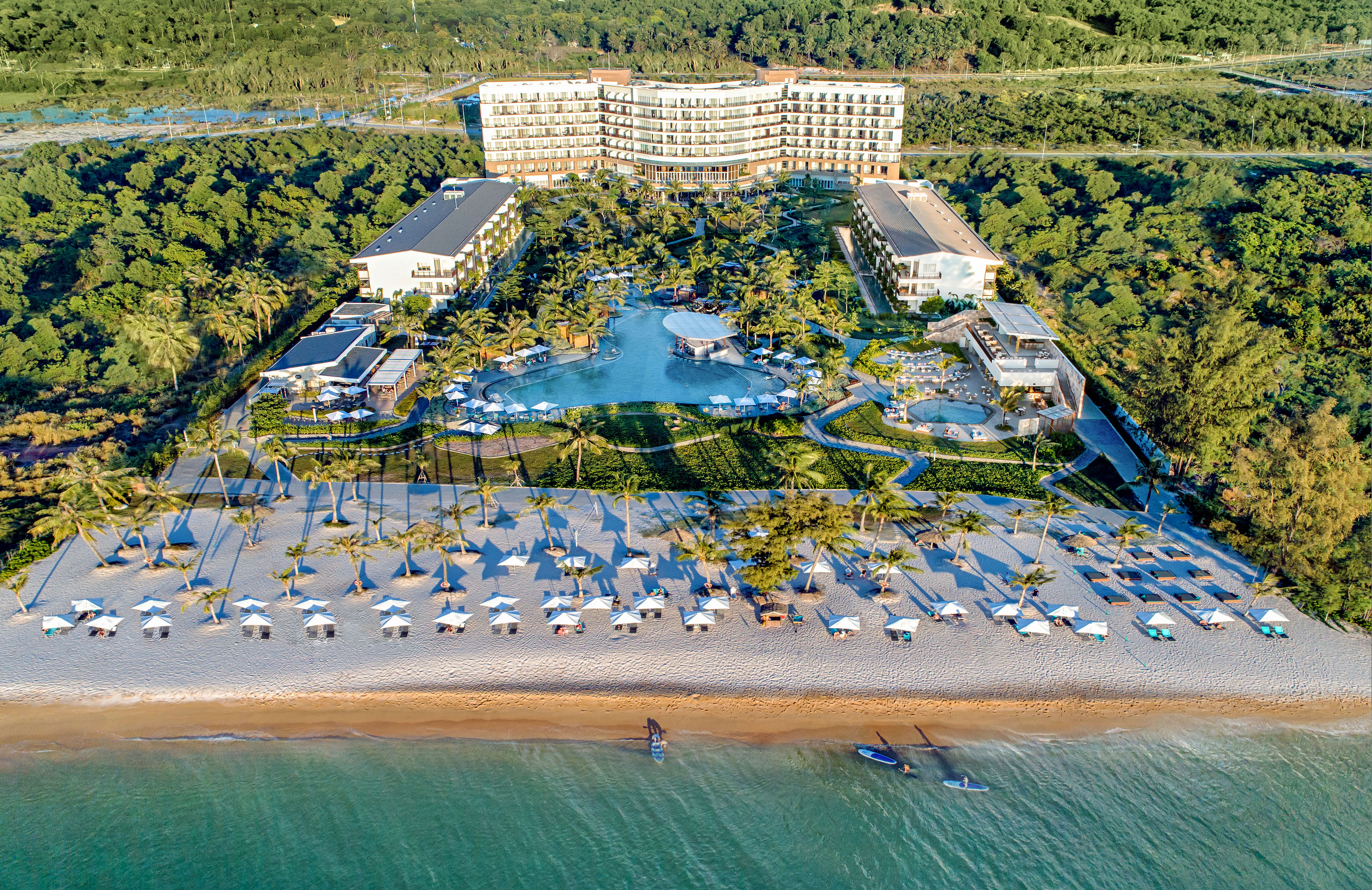 Tropical beach resort aerial: luxury hotel, pools, sandy beach, and ocean.
