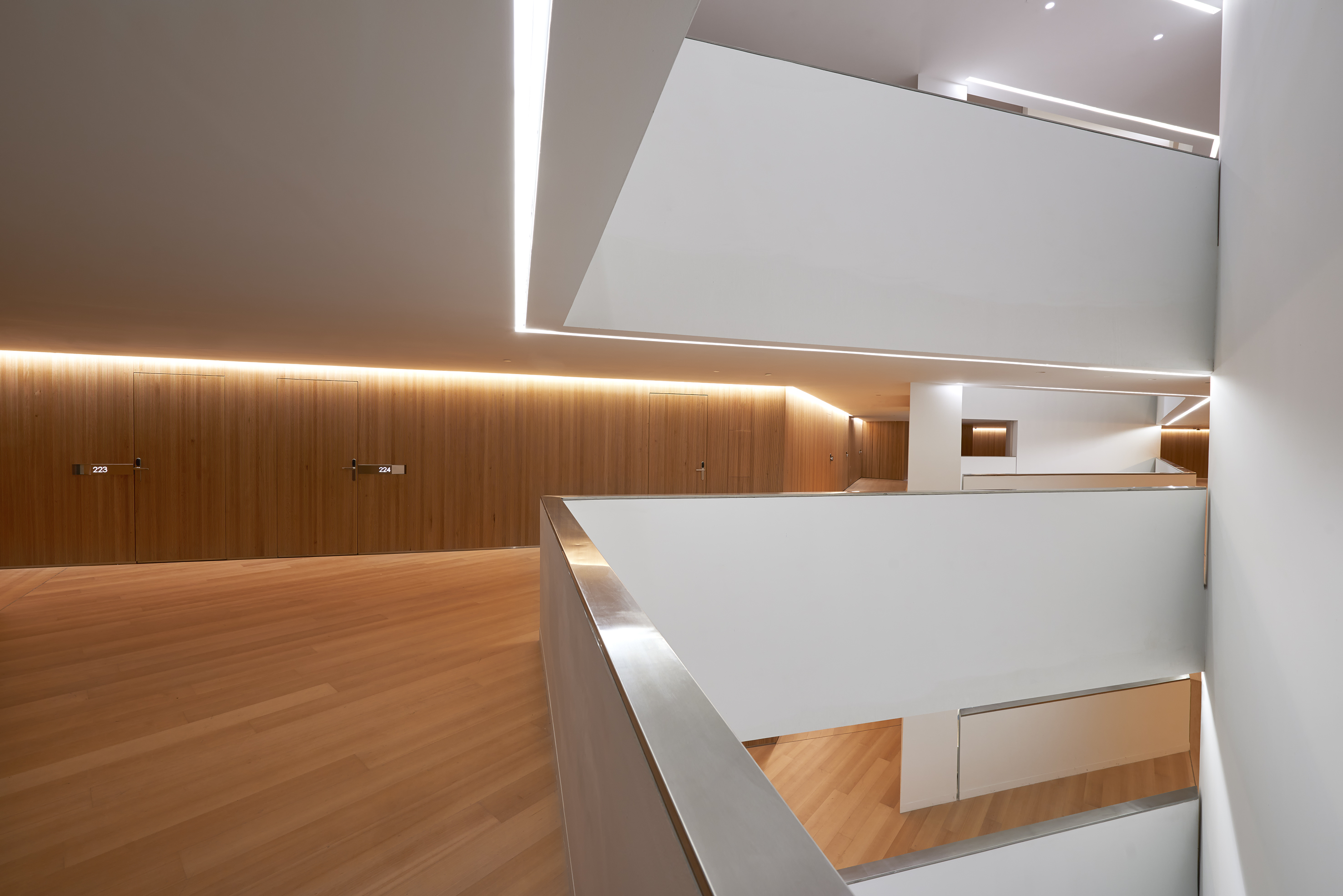 Modern multi-level interior with wood panels, white walls, and linear LED lighting.
