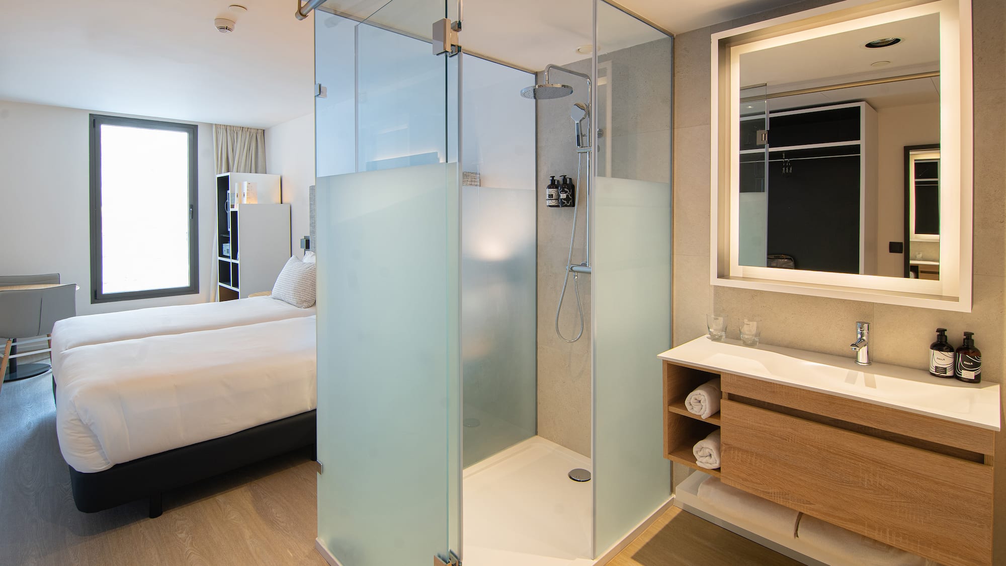 a bathroom with a glass shower and a bed