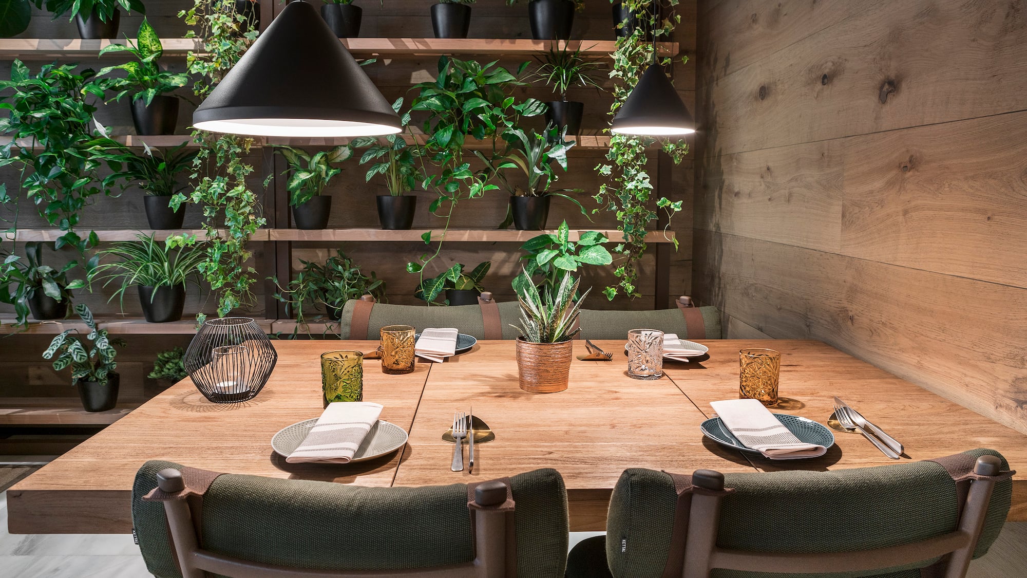 a table with plates and chairs in a room with plants