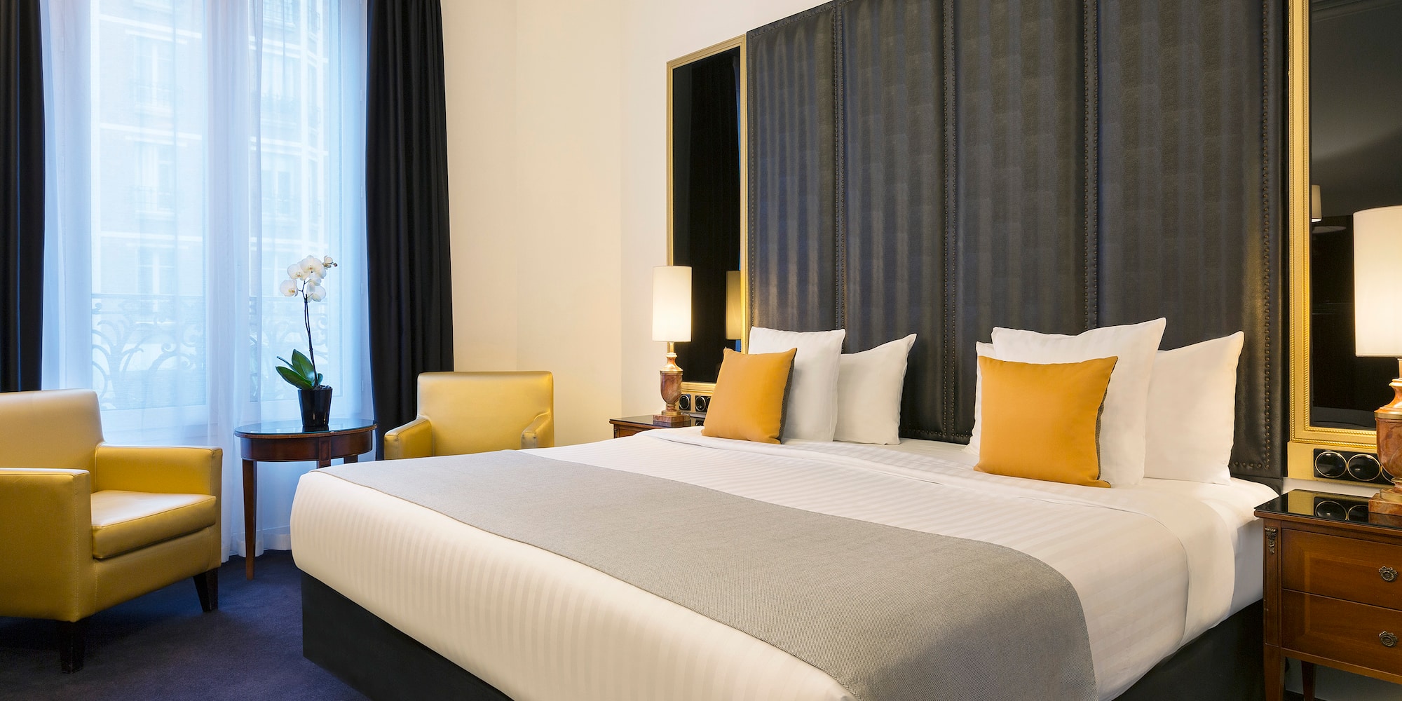 a bed with a curtained headboard and a chair