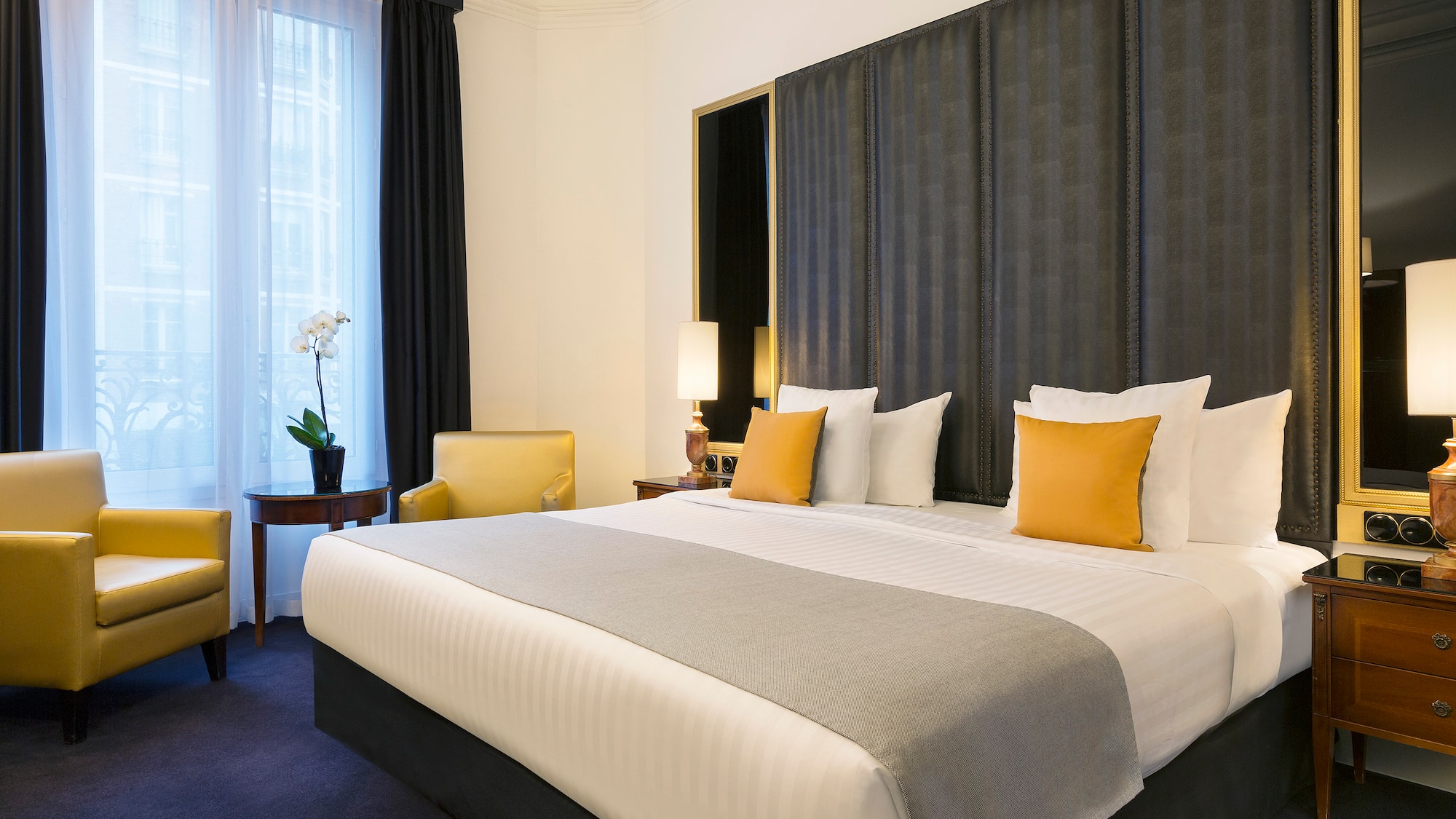 a bed with a curtained headboard and a chair