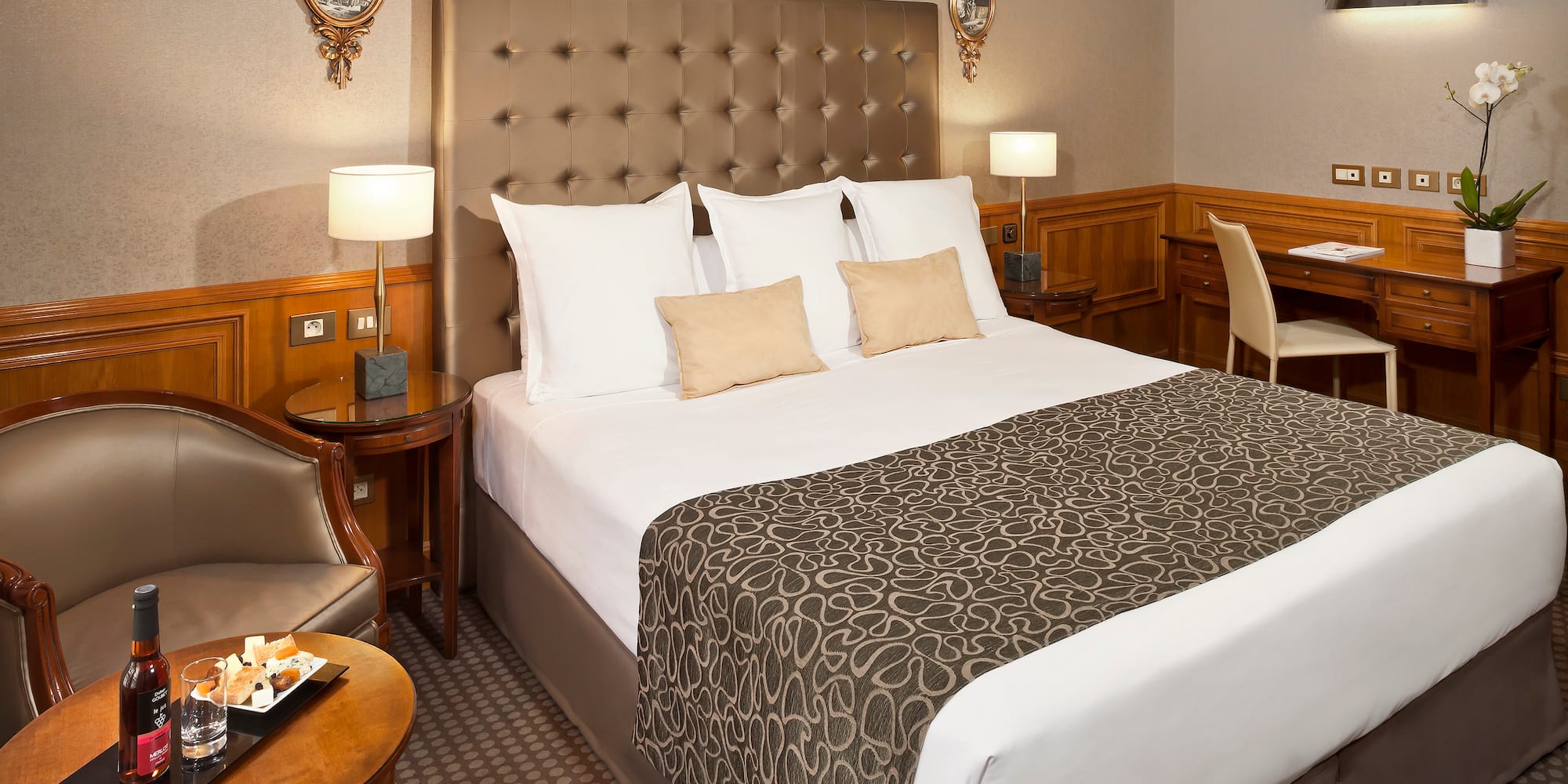 a bed with a headboard and a table with a tray and chairs