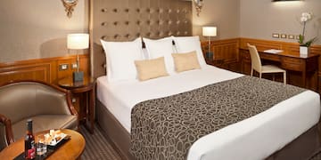 a bed with a headboard and a table with a tray and chairs