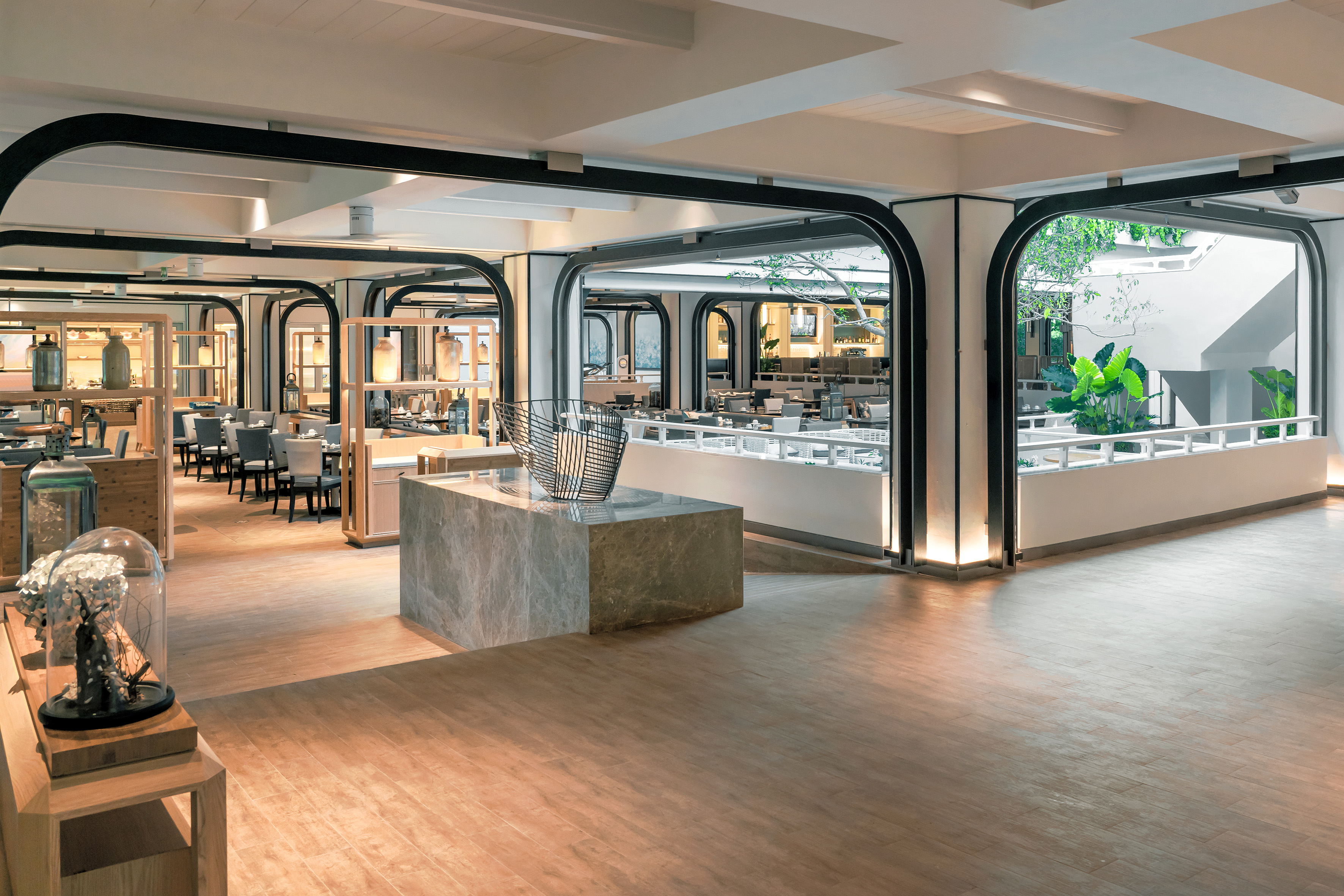 Modern restaurant with archways, elegant dining area, and outdoor garden.