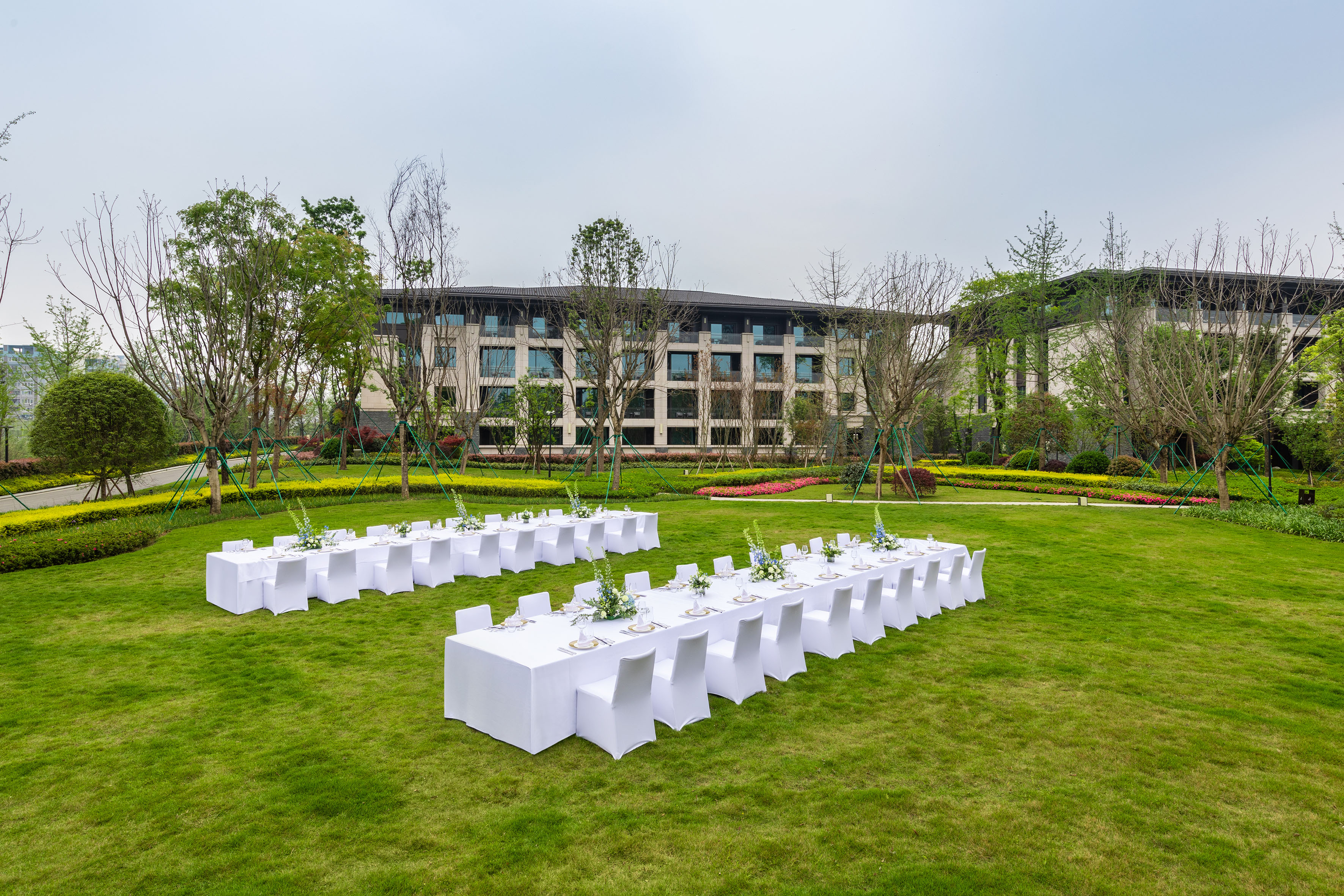 Outdoor wedding reception tables on green lawn, hotel garden venue.