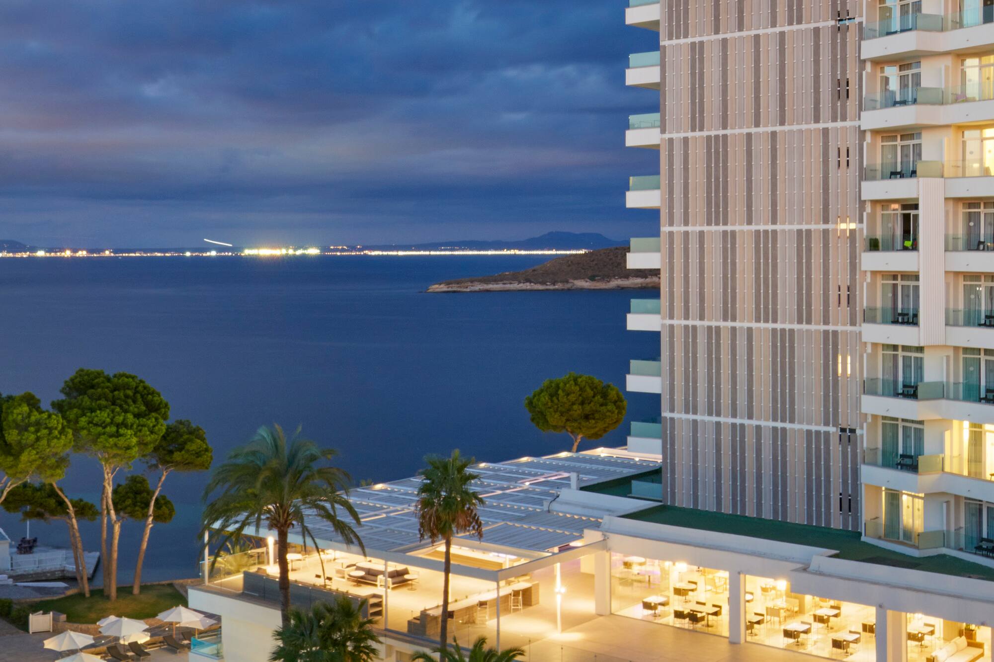 Melia Hotel at night, oceanfront with illuminated building and palm trees.
