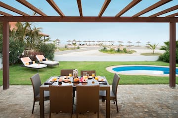 a table set for a meal outside with a pool in the background