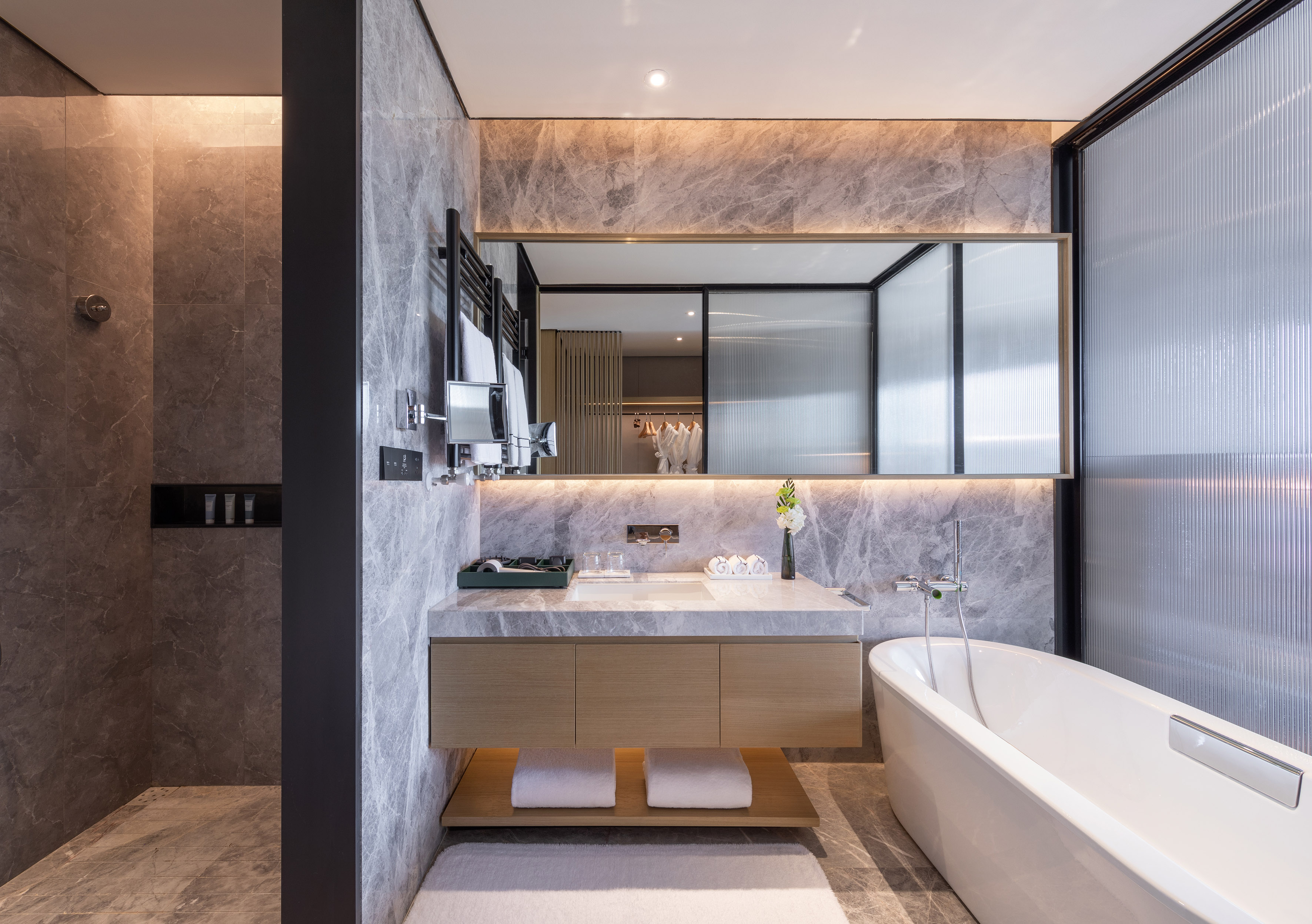 Modern marble bathroom with freestanding tub, vanity, and walk-in shower.