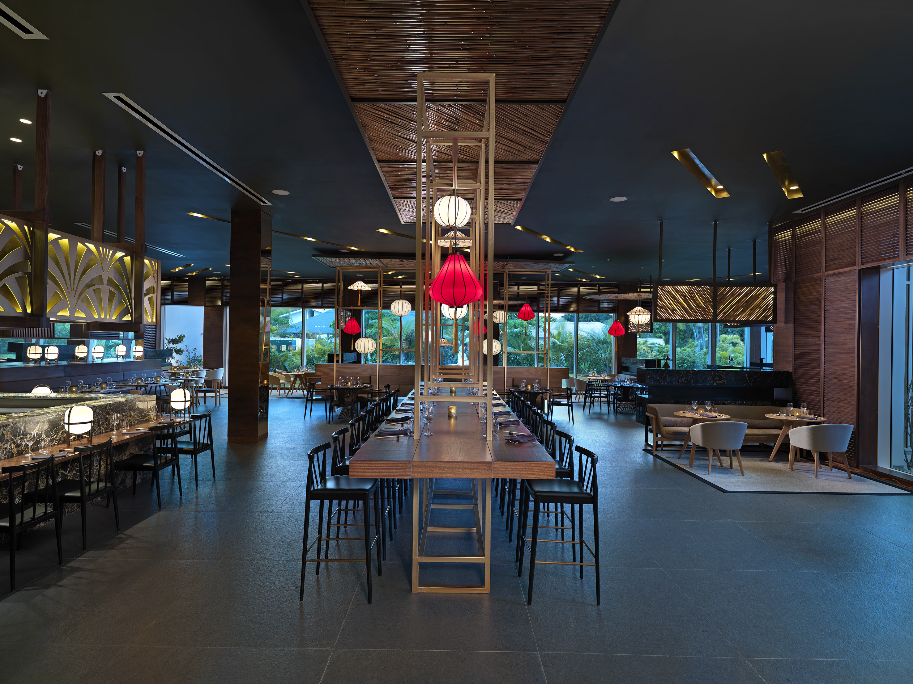 Modern restaurant interior with long table, red lanterns, and bar seating.