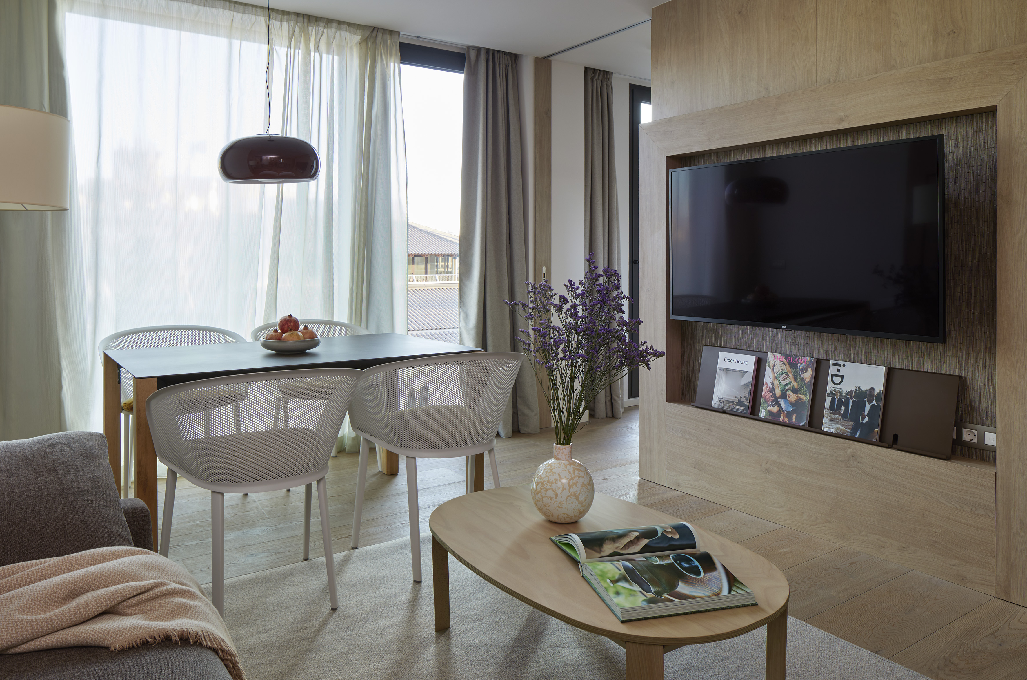 Modern open-plan living and dining room with TV, sofa, and wood floor.