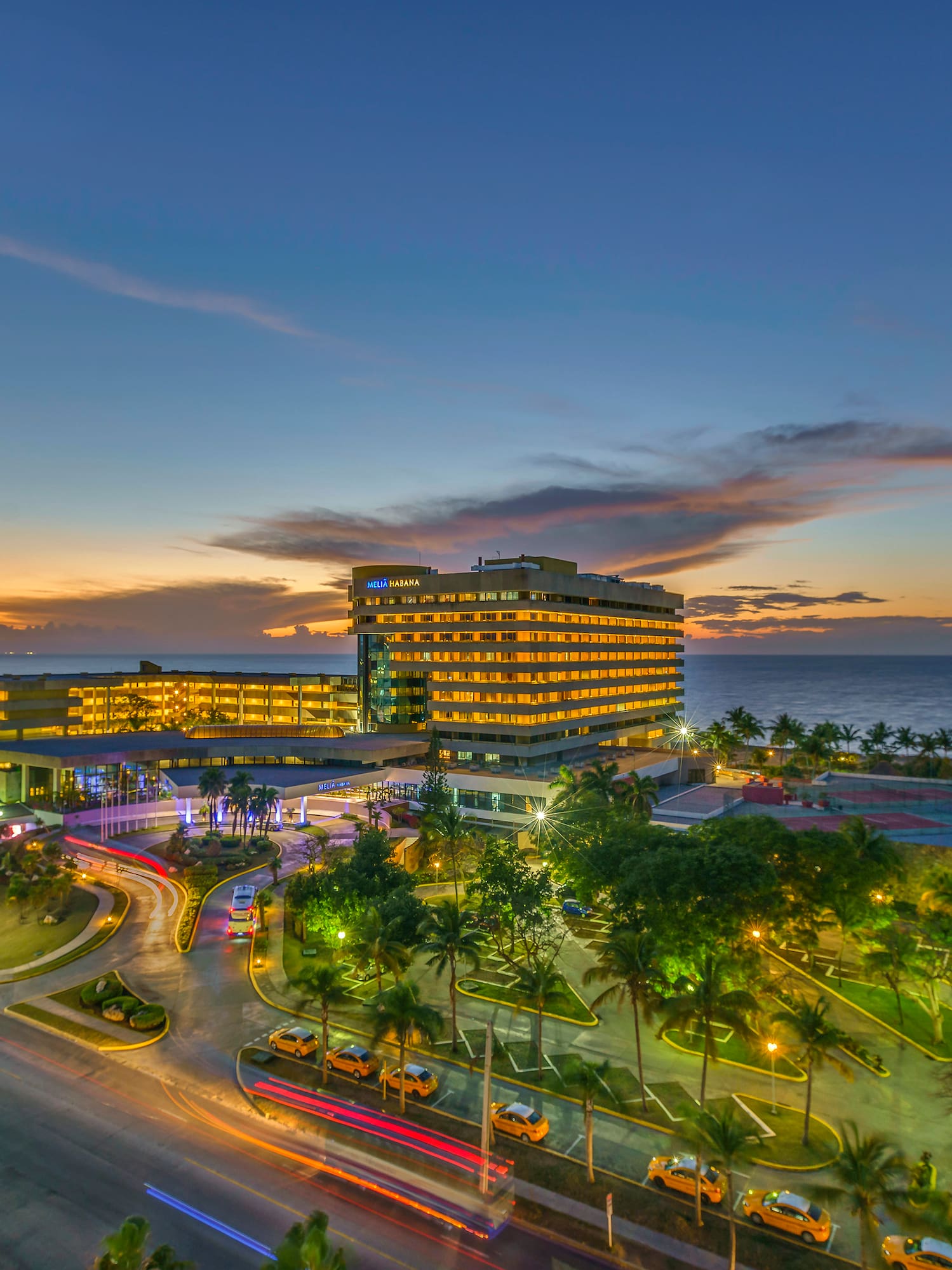 a building with lights on it and a road and trees on the side