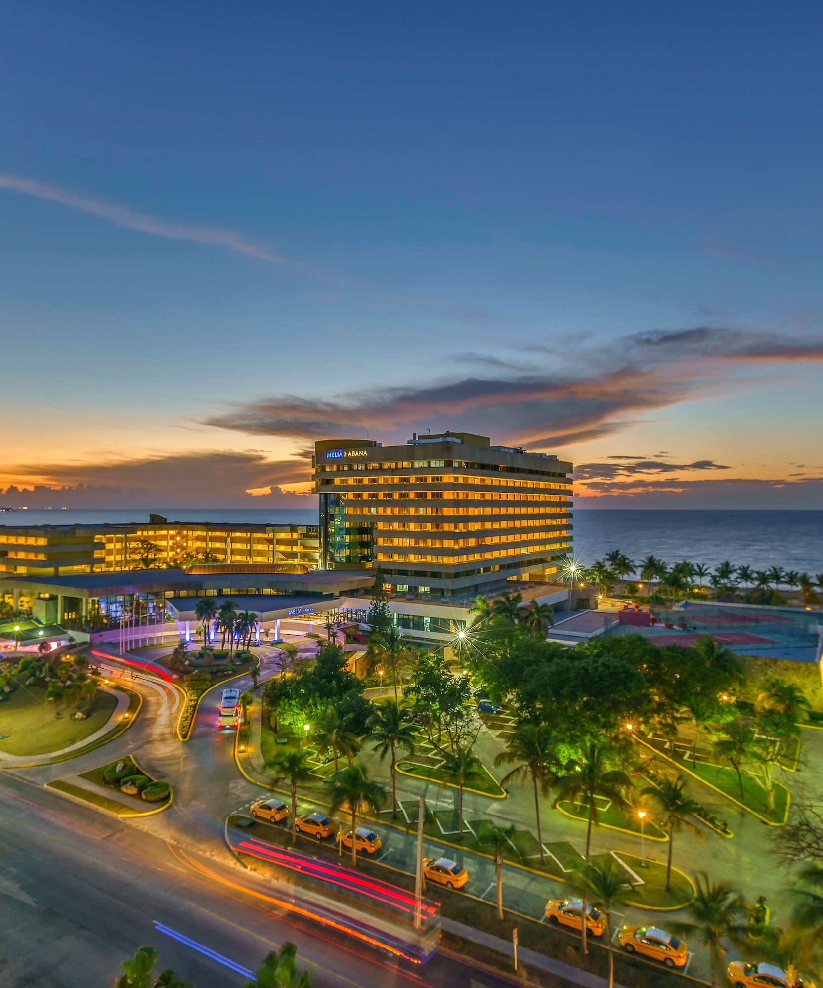 a building with lights on it and a road and trees on the side