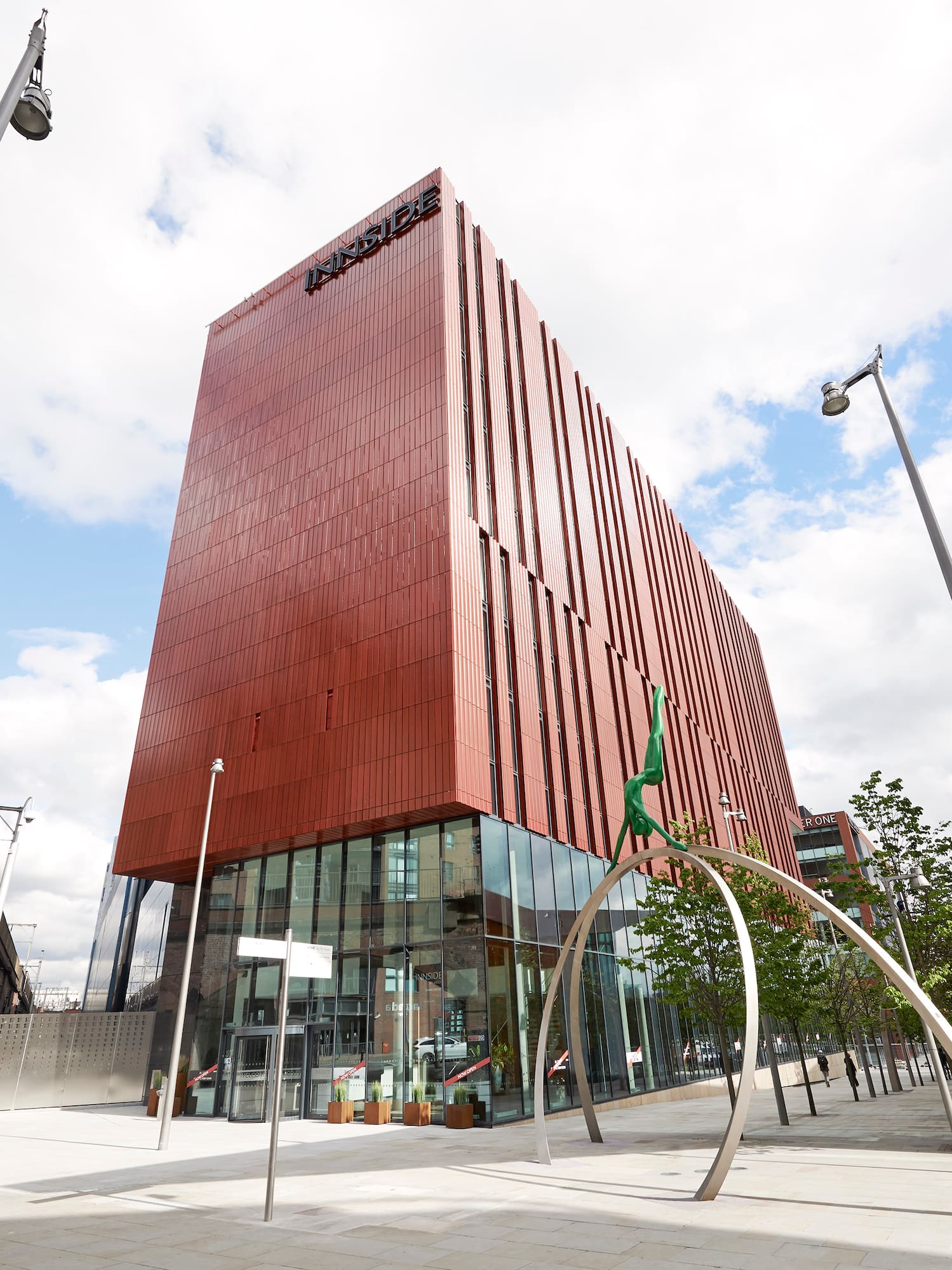 Modern INNSiDE hotel, tall red-brown building with glass entry, urban cityscape.