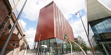 a building with a glass wall and a tree in front of it