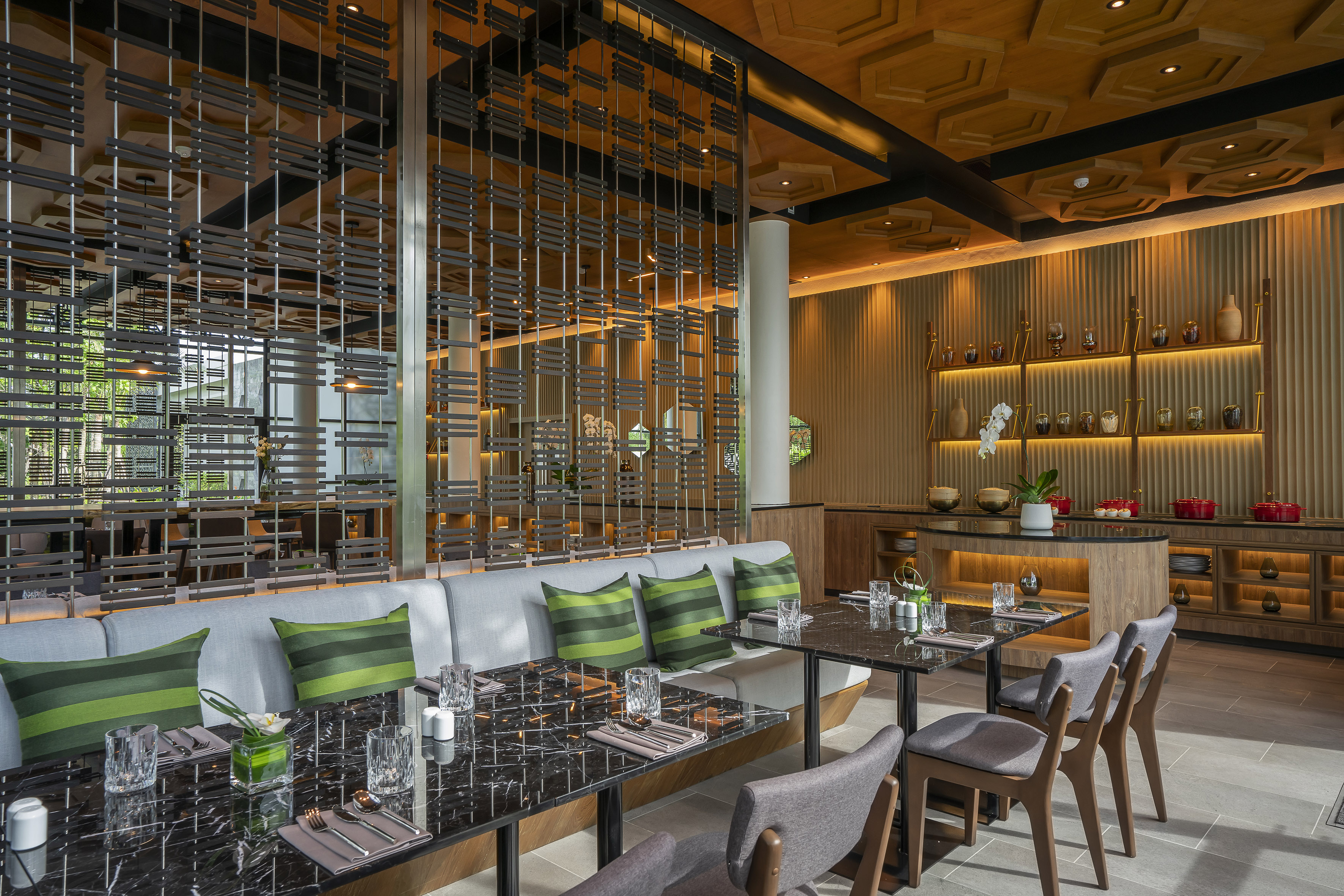 Modern dining room with green banquette, marble tables, and decorative screen.