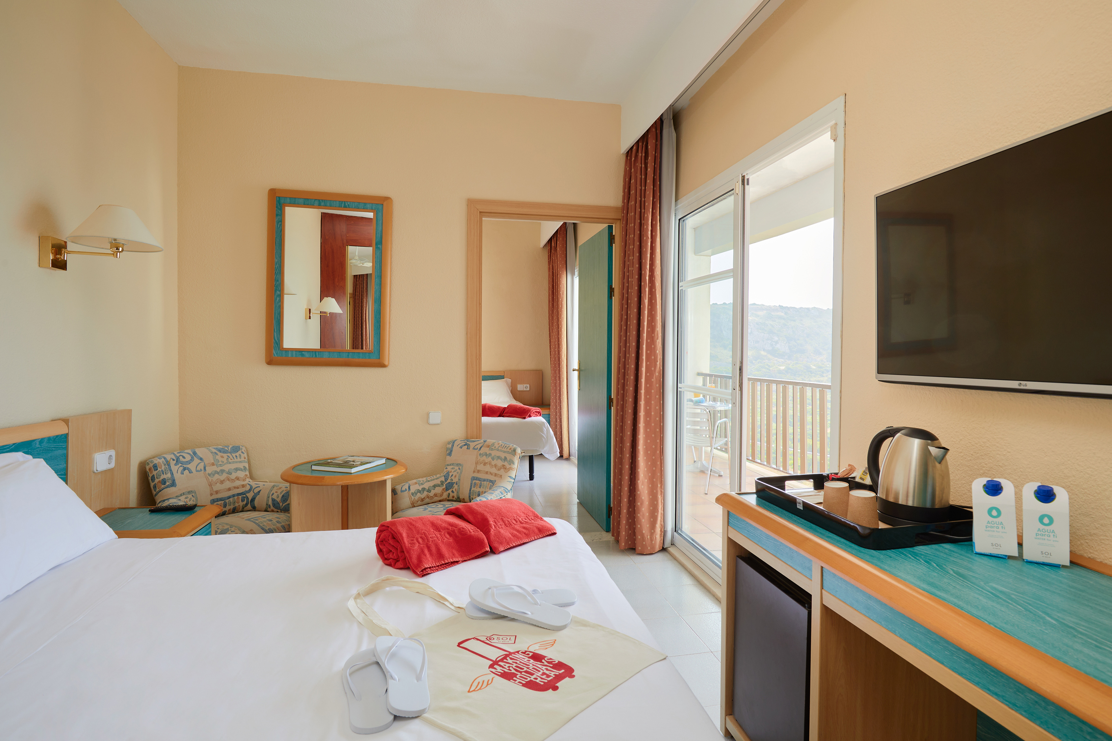 Hotel room with bed, balcony, sitting area, and connecting room.